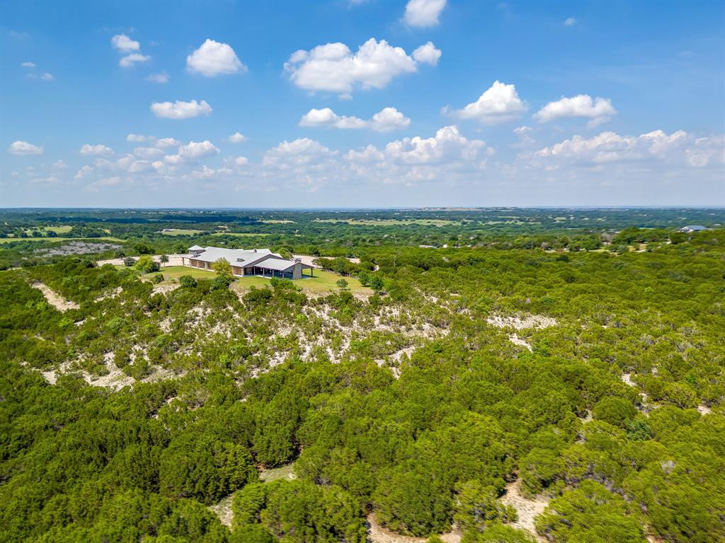 Perched atop the rolling hills of North Texas, the breathtaking Dove Ridge Venue offers an extraordinary opportunity to own one of the region’s most iconic event & wedding destinations. Spanning approximately 39 unrestricted acres with Ag Exemption sitting in Parker County, this remarkable property captures sweeping 360-degree panoramic views of vineyards & countryside, creating a setting that feels worlds away while remaining conveniently positioned within the DFW market. Architecturally striking & intentionally designed, the venue blends clean, elegant lines with expansive floor-to-ceiling windows that flood the grand ballroom with natural light & frame unforgettable sunset views across the surrounding landscape. Every detail of the estate was thoughtfully curated to create an elevated guest experience while supporting seamless large-scale event operations. The property features a spacious 9921sqft indoor reception hall, multiple outdoor ceremony locations, beautifully landscaped grounds, over 6000sqft of covered patios, dedicated bridal & groom suites, abundant on-site parking, & event-ready infrastructure designed for exceptional guest flow & functionality. The flexible layout allows for weddings, corporate retreats, luxury gatherings, private celebrations, & curated guest experiences alike. With strong regional brand recognition & an established reputation within the wedding & events industry, Dove Ridge offers both immediate income potential & long-term growth opportunity. The venue currently services approximately 100 booked events annually, with weddings already secured through 2027, creating consistent cash flow from day one while leaving room for future expansion & additional development opportunities across the rolling hilltop acreage. A rare offering where luxury hospitality, architectural beauty, and income-producing potential converge, Dove Ridge represents a premier legacy investment in one of North Texas’ most desirable & rapidly growing areas.