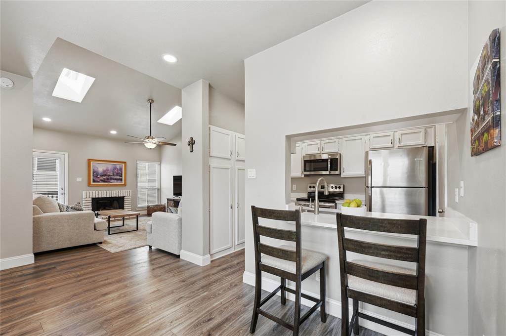 Experience the peak of modern North Dallas living in this stunningly renovated condo that radiates with natural light from morning until dusk. As you step inside, your eyes are immediately drawn upward to the soaring vaulted ceilings and skylights that create an airy, expansive atmosphere. The living room serves as a sophisticated retreat featuring a cozy brick fireplace and gorgeous new flooring that flows seamlessly into the dining area. The kitchen is a true showstopper for the home chef, boasting sleek white cabinets, stainless steel appliances, and a convenient pantry. Dramatic waterfall quartz countertops elevate the space, complemented by a breakfast bar designed for casual mornings or evening cocktails. Retreat to the spacious primary bedroom or enjoy the updated bathroom that reflects the same modern aesthetic found throughout the home. A private balcony offers a peaceful escape with a glimpse of the sparkling community pool. For ultimate convenience, the washer, dryer, and refrigerator are all included to make your move-in effortless. Rare for condo living, this unit includes a garage in the building with overhead storage for all your gear. Peace of mind comes standard with a recently replaced AC unit and new windows for maximum efficiency. Located in a secure gated complex with two pools and a grilling area, you are just one mile from the renowned Belt Line corridor. Enjoy instant access to the Dallas North Tollway, 635, and 75, putting the best shopping and dining in the city right at your doorstep. Take a first-person look at this gorgeous home! Click the Virtual Tour link to see the 3D Tour!