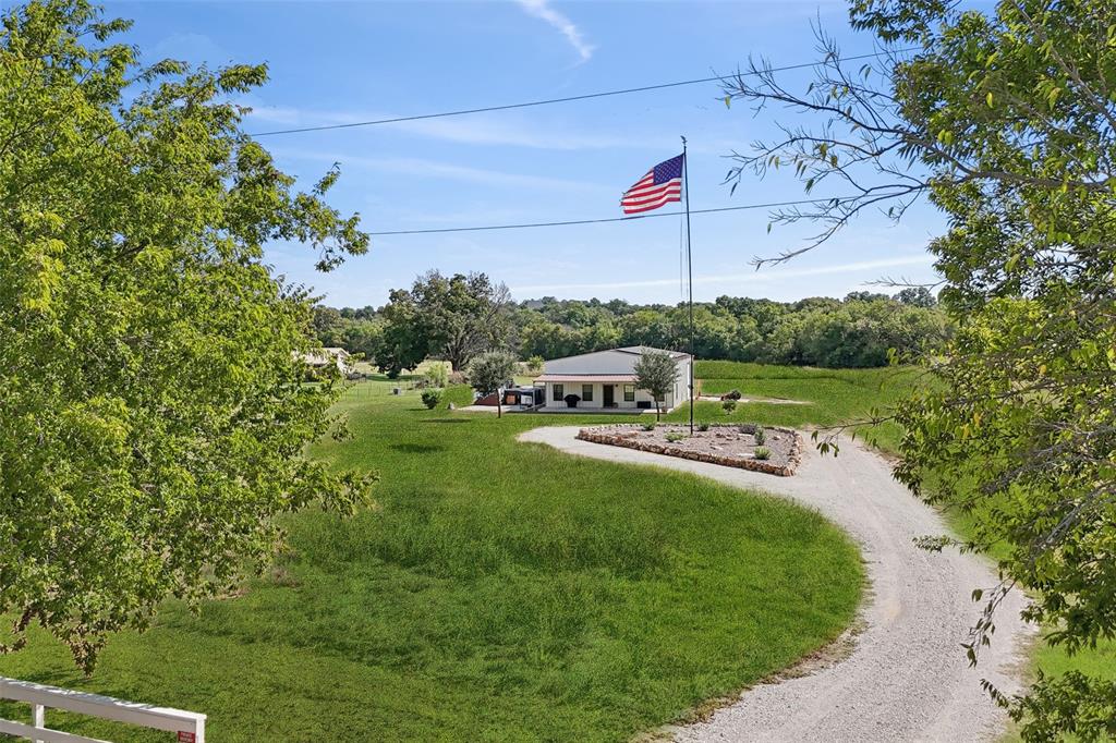 Connect with the listing agent for details!! Make your Texas ranch & barndominium dream a reality on this Ag exempt land with a contemporary Barndominum and room to grow! Haul in your equipment, drive in your livestock, and live off the grid with your own well, solar panels and septic tank! This beautiful lot is fenced and backs to Long Creek that flows to the Brazos River. Back Up Generator, brand new, never used, has been installed and will convey with the home. The cozy Barndominum features an open floor plan and designer touches. The modern kitchen offers built-in appliances, a breakfast bar with seating, recessed lighting, and ample storage space. The serene bedroom boasts an ensuite bath with dual sinks and a walk-in closet.  You will appreciate 1200 sqft climate controlled storage space above the living area and the spray foam insulated garage. Two large bay doors allow you to pull your boat or RV through. Additional approximately 1200 sqft space attached. Pallet racking in the garage conveys. Exempt for hay. Newly added gravel pad next to home for convenient RV parking. Don't miss out on this rare gem! The sale convey's 2 parcels which include the .5 acre with the Barndo and the remaining nearly 9.5 of Ag exempt mostly fenced land that backs to creek.