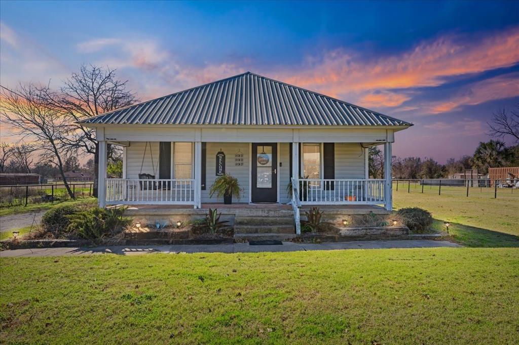 Well-maintained 2-bedroom, 1-bath home situated on 1 acre, offering a desirable country setting with convenient access to town. The home features a spacious office area leading to the primary bedroom with a walk-in closet and an attached utility room. The secondary bedroom is located near the living area and also includes a walk-in closet. The kitchen offers ample cabinet and counter space with an eat-in kitchen. Enjoy the covered, screened back porch—ideal for outdoor enjoyment. The property is well-suited for horses, featuring two large paddocks and a three-stall horse barn. Additional improvements include a large workshop with concrete flooring and 220V electrical service, which could be finished out for an additional living quarters, office, you name it. Property is accessed through an electric gate and is fully fenced with pipe fencing.  You may want to view the video featuring a tour of the home. Link shared in the driving directions.