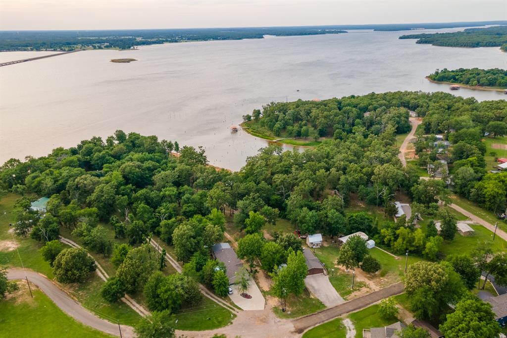 Fantastic lake front property with 600 feet of lake front on Lake Fork!! Perfect for a family looking to live the LAKE LIFE or for an Airbnb or VRBO investment property! Many vacation rentals along Lake Fork go for $150-$200 a night or more! This open concept home features 4 bedrooms, 2 bathrooms, large walk-in closets with double vanities in master bathroom! This property sits on two lots with one lot ready to add a dwelling or great for RV set up and parking! A separate building with an upstairs loft perfect for finishing out and making an additional income producing structure! Stunning views that pictures do not give it justice! Outdoor living at its finest with a wet bar on the back deck overlooking luscious greenery and Lake Fork. In the evening you will see families on their golf carts strolling the neighborhood waiving at neighbors as they enjoy the sunsets on Lake Fork. Community amenities features multiple fishing piers, boat ramp, clubhouse with pool table and games, outdoor pool, playgrounds, putt putt golf, basketball court and several picnic areas for large gatherings. Monthly potluck, karaoke and dances with live bands. LOTS 98 & 99 please reference last pictures for property boundaries. Don't let this opportunity pass you by!