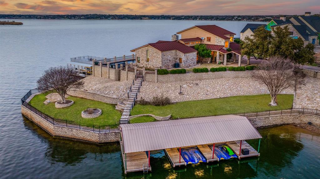 Welcome to this breathtaking lakefront estate on Lake Granbury, where stunning views and luxurious living come together in perfect harmony. This expansive lake home boasts 7 bedrooms, 4.5 bathrooms & sits on 2 lots with a private gated entrance. There is ample space for entertaining, relaxation, & making unforgettable memories with family and friends. The interior of this stunning lake home is designed for comfort and elegance, with high ceilings and beautiful picture windows. The open-concept living area flows seamlessly into the gourmet kitchen, perfect for cooking while taking in the majestic views of the lake. The kitchen is equipped with ample counter space & a large center island, making it the perfect spot for foodies & entertainers alike. The private primary suite is a serene retreat, complete with a spacious bedroom, large walk-in closet, & a luxurious en-suite bathroom with a separate shower and soaking tub. The primary suite also features private access to the outdoor living area, perfect for enjoying a quiet morning coffee or a romantic evening glass of wine. The outdoor living area is the crowning jewel of this lake home, with a sprawling patio, beautiful swimming pool and 2 private docks.  The outdoor living area is perfect for enjoying a hot summer day by the pool with family and friends or a relaxing evening by the fire. This stunning lake home has unobstructed breathtaking views of the lake. Enjoy watching Fireworks on the 4th of July as well as Amazing sunsets.  This area of the lake is know as striper alley for great fishing. The main boat dock features 2 boat slips a party deck up-top with a lounge area at lake level. The cove dock has 4 jet ski slips & 1 bay. This property has 730 linear feet of waterfront including deep water and a calm, secluded cove. This prime location on the lake home offers endless opportunities for water sports, fishing, and exploration. It is only 15 minutes to HEB & 30 min.to FTW.  Welcome to your lakefront paradise!