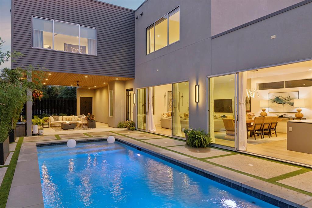 Inspired by iconic West Coast architecture, this striking modern residence was thoughtfully designed for a refined, design-forward lifestyle. Centered around a dramatic resort-style pool, the home seamlessly blends indoor and outdoor living through expansive sliding glass walls that open to a covered lounge patio ideal for year-round entertaining.

Sophisticated interiors showcase museum-finish walls, 8-inch rough-cut wood plank flooring, and curated designer lighting throughout. The chef’s kitchen is both sleek and functional, featuring Dacor black stainless appliances, quartz countertops, low-profile custom cabinetry, and elegant under-cabinet illumination.

The serene first-floor primary suite offers tranquil pool views and a spa-inspired bath adorned with Porcelanosa tile, luxurious finishes, and spacious walk-in closets. Upstairs, a generous second living area or game room with wet bar creates the perfect retreat for entertaining, accompanied by two additional en-suite bedrooms and baths.
