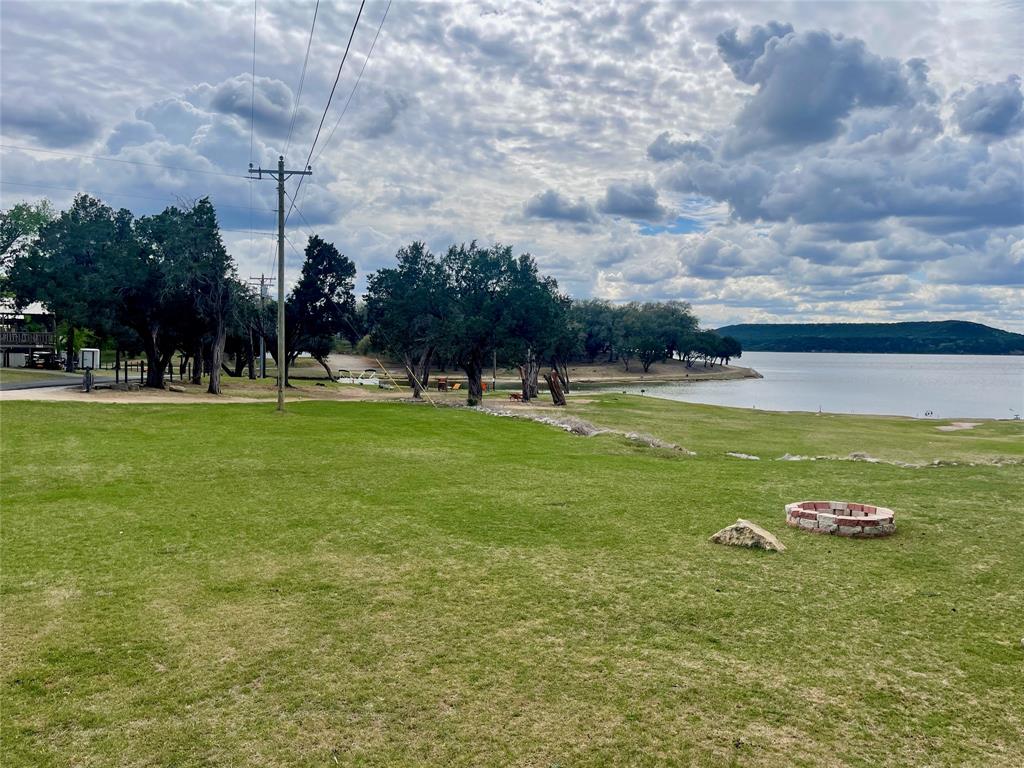 BRING YOUR OFFER! This cute as can be furnished lake cabin in the friendly Golden Cove community, located on the peninsula of Possum Kingdom Lake, is just waiting for YOU! With 2 bedrooms, 2 showers, a large living room, efficient kitchen, and a combo washer-dryer - all updated over the past few years - this cabin makes an ideal weekend getaway or vacation spot. Situated within walking distance to the swim cove, featuring magnificent water, sunset, and vista views from the deck, you can entertain large groups or keep it cozy with just you and the pets (separate fence for them included)! The wraparound deck, with one portion covered and one portion open, offers space for cookouts or parties with all the gang, coffee under the large shade tree as you watch the neighborhood deer stroll by, or relax with a drink as you enjoy the sunsets or starry nights after a day on the lake. In addition, you'll have covered parking and a storage shed at the back of the house for keeping tools, toys, etc. The Golden Cove community amenities include a boat ramp, courtesy dock, pavilion, onsite waste center, rentable storage units, and rentable cabins for the overflow of guests you'll have once your friends and family get to experience the PK Lake Life!  The centralized lake location of this community puts you right in the heart of the Great Lake of Texas ~ around the bend from Sandy Beach, a short boat ride to the West Side and multiple on-water dining options, not far from Hell's Gate or the dam at the end of PK. But if you don't want to be out on the lake, you can wade in at The Cove and join your new Lake Family for some floating and fun in the sun. The listing is for the improvements only on a lot leased from Oak Wood Properties.  The current lease fee is approximately $850 per month; a lease application must be submitted to and approved by Oak Wood prior to closing.  Come take a look at this sweet place and get your lake spot secured so you can start making lifetime lake memories!