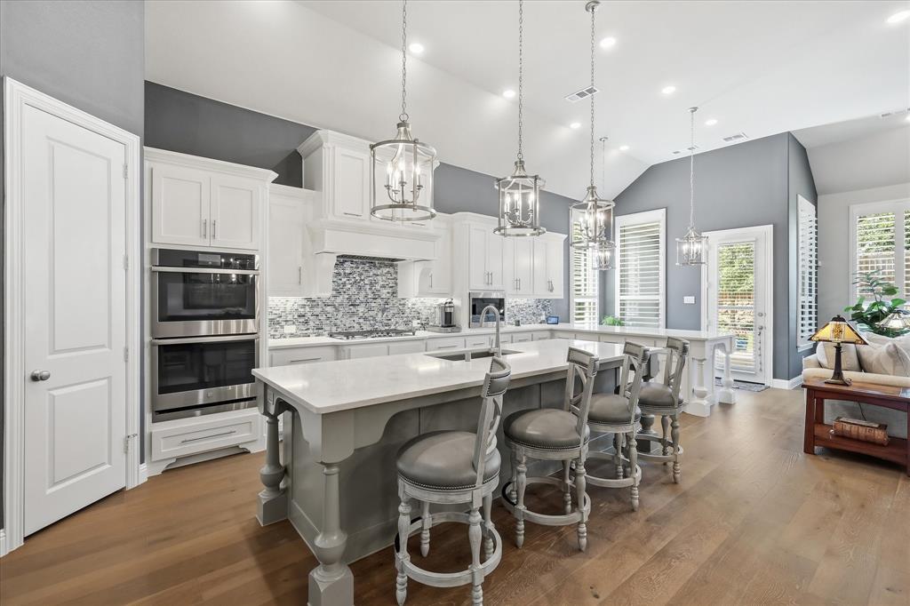 Experience the ultimate single-story luxury with this -magazine-worthy- Highland Homes masterpiece,positioned in the sought-after Canyon Falls community within walking distance to both Argyle South Elementary and Argyle High.As you enter, you are welcomed by a long, elegant foyer leading past a private front office with French doors. This designer-curated and highly customized home offers a seamless blend of elegance and effortless living, featuring 4 spacious bedrooms, 3.5 baths, and an atmosphere highlighted by soaring 13-foot ceilings and solid core doors. The chef’s kitchen boasts double ovens, a statement backsplash, under-counter lighting, and pull-out spice corbels. A standout feature is the expansive peninsula with extra seating, providing convenience for large-scale entertaining, grazing, or everyday living. The kitchen flows into a living room anchored by a dramatic stone fireplace. For quiet evenings, enjoy the dedicated media room or retreat to the extended owner's suite, a serene escape, with spa-like bath with dual sinks, vanity, a luxury garden tub, and his and hers large walk-in closets. Custom finishes adorn every corner, from upgraded wood plank flooring and designer light fixtures to custom plantation shutters.Utility spaces are impressive, with a laundry room boasting custom cabinets and extensive counter space.The oversized 3 car garage has epoxy flooring and overhead storage racks. Step outside to your private backyard sanctuary, where meticulously manicured landscaping and lush flower beds frame an extended patio equipped with an electric shade for outdoor living space. Living in Canyon Falls means embracing a nature-focused lifestyle with internet, cable, and front yard maintenance included in the HOA. Residents enjoy full access to amenities, including the Flower Mound Canyon Falls Park, a fitness center, two resort-style pools, splash pad, fishing ponds, a dog park, and miles of trails, with future pickleball courts coming soon.