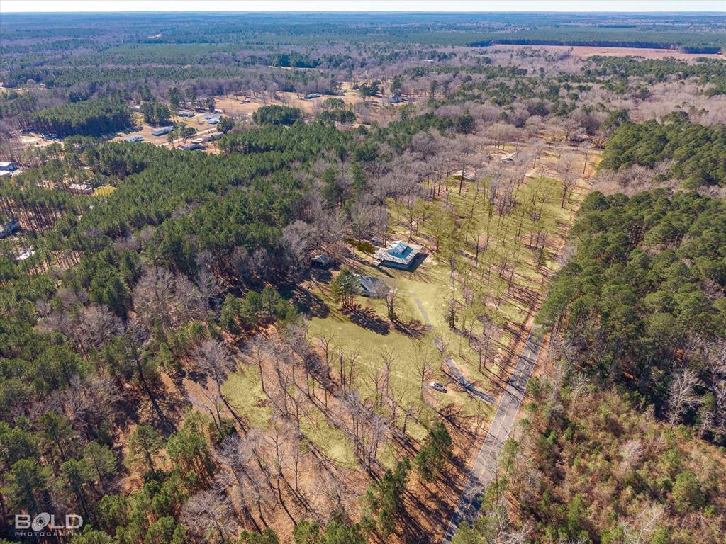 This rare find in the heart of Benton sits on approximately 30 acres of beautiful land featuring mixed hardwoods, riding trails, a stocked pond, and multiple outdoor buildings—perfect for the outdoor enthusiast. Offering an exceptional blend of comfort, functionality, and country living, the home has been thoughtfully updated with fresh interior paint, new carpet, updated kitchen appliances, a newer roof, and a whole-home generator for added peace of mind.

Inside, you’ll find a warm and inviting living area centered around a cozy fireplace. The home features two spacious bedrooms and three full bathrooms. The unique primary suite includes separate bathrooms, providing added privacy and convenience. A sunroom and dedicated office offer flexible living space and could easily be converted into a third bedroom.

Step outside and enjoy your own private retreat with scenic trails, a stocked pond, and a picturesque mix of open land and mature trees. The impressive barn and workshop feature a brand-new roof, expansive concrete space, and newly installed full-circle lighting. An unfinished upper level provides endless potential for additional living space, guest quarters, or a creative studio.

With ample room for parking, storage, and hobbies, this one-of-a-kind property offers privacy, versatility, and room to grow—all in a highly desirable Benton location.