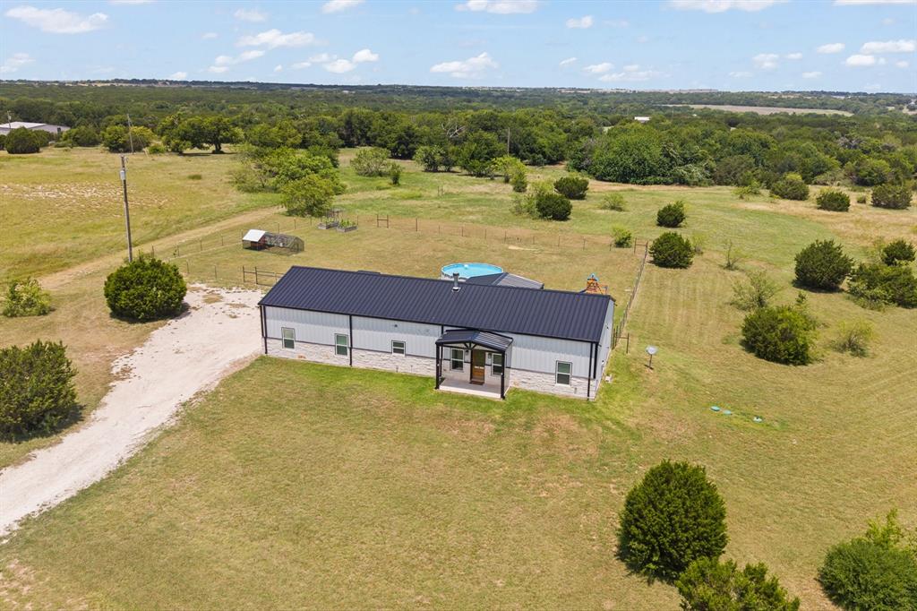 Country living meets modern design on 5.05 acres in the Ranches at Eagle Ridge! Built in 2023, this barndominium-style home offers 3 bedrooms, 2 bathrooms, and 1,500 square feet of living space, plus a 757-square-foot insulated and finished garage. A 48 inch stone skirt on the front elevation adds a polished, durable touch, while spray foam insulation throughout keeps the home efficient year-round.

Step inside to an open-concept floor plan filled with natural light, quartz countertops throughout, and a butcher block kitchen island that anchors the space as it flows seamlessly into the living and dining areas — perfect for everyday living and entertaining alike. The spacious laundry room offers additional counter space for folding, organizing, and storage.

Outside, unwind on the covered front porch or the expansive covered back patio overlooking your private acreage. The fenced backyard area is ideal for kids or pets, while the remaining land is yours to garden, raise livestock, or simply enjoy peaceful country views.

Located outside the city limits with no city taxes, this property delivers the freedom of country living just minutes from Rio Vista and Cleburne for shopping, dining, schools, and everyday conveniences. Served by a private well and septic system, this is the rare combination of a newer home, modern finishes, and real acreage. Schedule your showing today!