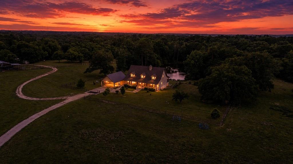 3-level custom brick home on 88+ acres in Franklin County, just minutes from Lake Cypress Springs, Mt. Vernon &Winnsboro. The walk-out basement includes 2 bedrooms, extra room, full bath, kitchen area, wood-burning stove, storm room, all-house equipment room with separate HVAC for basement, and a 6-foot covered patio with hot tub & view of the pond. The main level features a 60-foot covered front porch with access to a 60x12 back porch, mostly screened in, overlooking the spring-fed pond stocked with bass & catfish. Inside, the spacious living room offers teak wood floors, 10-foot ceilings, wood-burning stove, pond views, and is open to the dining area & large kitchen. The kitchen includes granite, SS appliances, 2 refrigerators, 6-burner propane cook top, double convection oven, pantry, and an additional storage. The main bedroom features a bay window overlooking the pond, along with large bathroom with double vanity, walk-in shower, jetted tub, propane wall heater, & spacious walk-in closet. A large guest bedroom on this level includes it's own bath with walk-in shower. The third level (1,426 sq ft) is air-conditioned, insulated, & includes a half bath & geothermal HVAC equipment. There's an elevator shaft opened from the main level to the top level currently used as a lift for moving items. Exterior features include a 2 car detached garage with side covering, 2 car front carport and whole-house generator. The land offers abundant timber, (used for stairs and basement decor), as well as fenced acreage & pipe corral for cattle, metal28x60 shed or equipment, as well as a 23x21 concrete floor metal shed, 36x20 concrete floor metal shop with overhead &walk doors. There's a 1224 SF guest house with carport & well that's separate from the well for the house. The large pecan orchard could well be a cash crop if wanted. This place has it all!