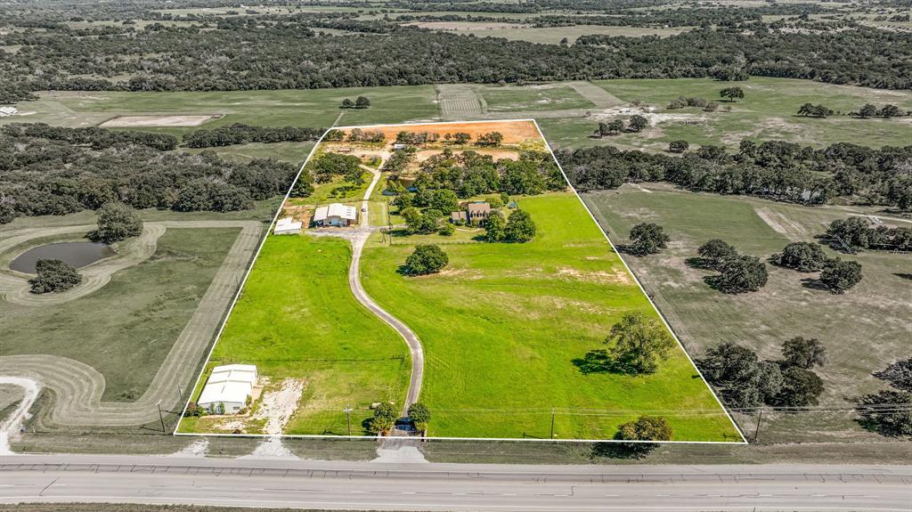 This beautiful 4-bedroom, 3.5-bath home is situated on 16.04 acres along N Hwy 281, just minutes from Stephenville. The impressive rock home features the master suite on the main floor, while three additional bedrooms and two baths are located upstairs. The open-concept lower level boasts a striking gas fireplace that can also be used as wood-burning. The kitchen is equipped with commercial-grade stainless steel Viking appliances, granite countertops, and custom cabinetry.

 Heated pool with hot tub and Aqualink system. Roping arena, cabin, a 4-stall barn with heated water, a tack room, and a feed room. There's also a second barn with two stalls and a feed-tack combo room, irrigated greenhouse and garden area, chicken coop, 3 RV hookups, and a spacious 40x60 workshop with an apartment and provides a separate entrance, ideal for your business needs.  New well pump 2024. The property has coastal and has produced over 40 round bales this year.