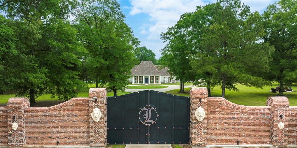Welcome to your luxury estate nestled on 35.69 acres of pristine land in the heart of East Texas.  The property is just minutes from the LA Border.  This property offers a large 5 acre stocked lake with tons of different types of fish, amazing oak trees, and a custom built gazebo, here you will also find the ultimate in exceptional living that is surrounded by peace and tranquility.  The home boasts a parlor room, four spacious bedrooms, floor to ceiling windows overlooking the beautiful lake, 10 ft flat, 11 ft flat, and a 21 ft vaulted ceiling.  Barrell ceilings grace the entry and the primary bath.  The kitchen is a Chef's dream with double islands, leathered marble countertops, custom glass inlays, dovetail drawers, imported hardware and much more.  Also the kitchen has Thermador appliances, ample storage, and a large butler's pantry with marble backsplash and solid wood custom built cabinets.  Brazilian hardwood floors give this home the luxury feel you have been looking for.  Pair all of this with the restoration hardware fixtures, all custom wood moldings and you have a true luxury home.  As you approach this property, you will be immediately struck by the beauty of the custom hand carved granite lion heads accented along the nine foot to 14 foot brick roman style wall surrounding the solid iron custom gate.  The English bond, flemish bond, and herringbone patterns make this entry wall simply breathtaking.  It is truly a work of art.  The gated entry creates an impressive atmosphere that sets the tone for the rest of the property while feeling like you're the only people within miles of the place.  There is also a bridge that spans across the 5 acre lake that was the original railing restored from the historic Logansport bridge that connected Texas and Louisiana.  There is also a large deck by the lake for sunbathing while everyone else is trying to catch their fish of the day!  Do not miss your chance to own your own private retreat for you and your family!