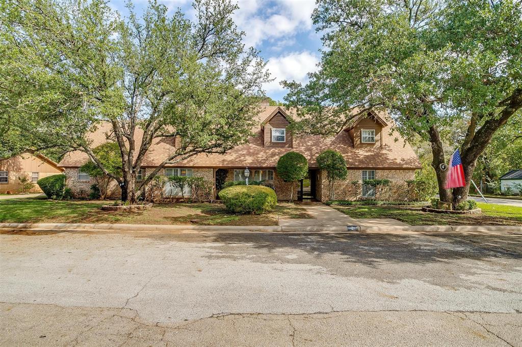 Charming 3,400sqft brick home with an enchanting backyard paradise. Step inside to discover a expansive living area with walls of windows & adobe brick floors. This home boasts an array of inviting spaces, from the large formal dining to the oversized breakfast room & an elegant formal sitting room. Spacious kitchen with granite counters, walk-in pantry, & room for a sitting area. Primary suite down with 3 beds & 1 bath up. Nestled in a great neighborhood, the property is graced by large, mature trees & sits on a picturesque corner lot. You'll relish the opportunity to entertain beneath the stars on the lengthy covered porch, open patios, & amidst the sprawling gardenscapes that adorn the backyard. Recent updates include a new carpet throughout the home, a new oversized carport, & a small workshop with electricity for your projects & hobbies. Just minutes from downtown Mineral Wells, you'll have easy access to local amenities.