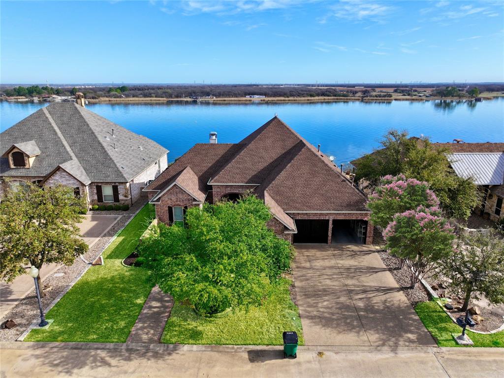 Seller offering a 10,000 dollar painting allowance!
The panoramic views of Lake Granbury from this elevated home are nothing short of breathtaking—sunrise, sunset, and every moment in between. Guests are welcomed through a charming front courtyard, an ideal spot for seasonal blooms, into an interior that is exceptionally clean, beautifully maintained, and thoughtfully designed. The open-concept layout maximizes the scenery with a nearly uninterrupted wall of windows spanning the back of the home. Inside, warm Southwestern-inspired accents add personality, while the spacious living room invites relaxation with its gas log fireplace and custom built-ins.
The kitchen shares the same sweeping lake view and offers a large breakfast bar, center island, walk-in pantry, and elegant white cabinetry—perfect for everyday cooking or hosting friends and family. All three bedrooms feature private en-suite bathrooms, providing comfort and privacy for everyone. The primary suite overlooks the water and includes a spa-inspired bath with jetted tub, separate walk-in shower, and a seated vanity. A convenient guest powder bath off the living room adds appeal to this floor plan.
Outdoors, the expansive covered back porch is your front-row seat to morning coffee moments and evening grilling. When it’s time to enjoy the lake, take the HOA-maintained cart path directly to the shared community boat dock—no stairs required. Boat slips are available for lease, Irrigation water is obtained from the lake and lawn maintenance (excluding flower beds) is provided by the HOA, making lake living effortless. Located within a small gated community, this property is perfect as a full-time residence or a weekend retreat and features a NEW ROOF in 2025 for added peace of mind.  
Don’t miss your chance to claim this extraordinary slice of Lake Granbury paradise.