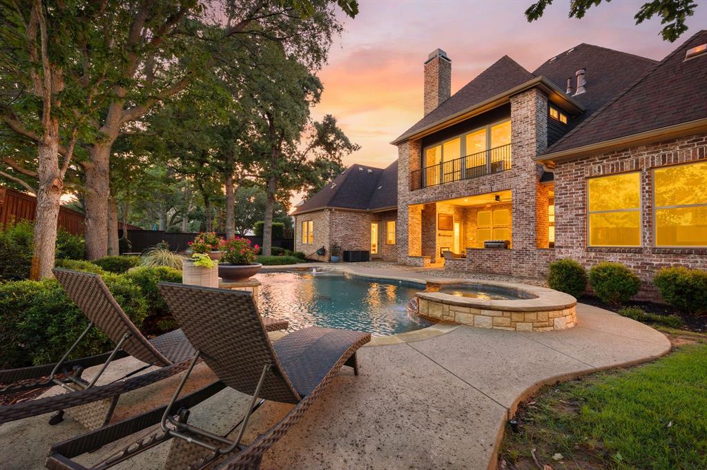 Welcome to this stunning home in the sought-after Colleyville neighborhood of Whittier Heights.  Rich hardwood floors flow throughout the thoughtfully designed floorplan, complemented by an oversized 3-car garage and exceptional indoor-outdoor living spaces. The spacious primary suite is a true retreat, featuring a cozy fireplace, dedicated desk area, oversized walk-in closet, and a versatile bonus room perfect for a private office, workout space, or nursery. A secondary bedroom is conveniently located downstairs, offering flexibility for guests or multigenerational living. Designed for entertaining, the home features a beautiful upstairs bar area with built-in cabinetry, gameroom and a dedicated home theater. Upstairs, you’ll also find two generously sized bedrooms, each with private en suite bathrooms. An additional upstairs living area features sliding doors that open to a balcony overlooking the sparkling pool, while the spacious covered patio below offers a fireplace and built-in grill—perfect for year-round entertaining. The backyard is a private oasis complete with lush landscaping, charming stone pathways, a beautiful pool with water features, and a relaxing hot tub. Homeowners enjoy the best of both worlds with the option to attend Keller ISD or take advantage of open enrollment to GCISD. This exceptional Whittier Heights property truly offers luxury living in an unbeatable location.