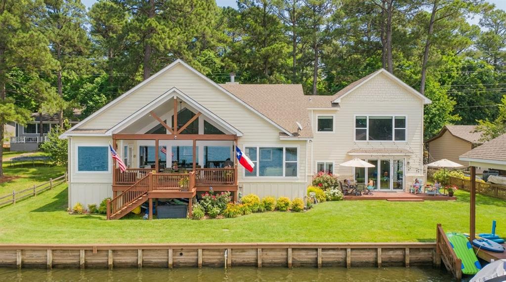 Fabulous waterfront home on beautiful Lake Cypress Springs, located in the desirable Tall Tree community. This spacious lake home features 4 bedrooms and 3 and half baths with an inviting open floor plan designed for comfortable living and entertaining. The family room showcases vaulted ceilings, a stone wood burning fireplace, and a wall of windows providing amazing views of the lake. The fully equipped kitchen offers granite countertops, stainless appliances, a breakfast bar, and a walk in pantry. A convenient mud room, laundry room, and work office station with lake views add everyday functionality. The split primary suite features double sinks, a jetted tub, and a walk-in closet, while two guest bedrooms are located downstairs for easy access. The floored oversized garage game room with HVAC splitter offers flexible space and also enjoys a nice view of the lake. Flooring includes a combination of laminate and carpet throughout the home. Upstairs, a dormitory style bunk room provides plenty of sleeping space with three sets of bunk beds and a media projector, perfect for guests and family gatherings. Outdoor living is exceptional with a lakeside covered deck with shades, ideal for relaxing and entertaining. The property also includes a single slip boathouse with a jet ski lift, offering convenient access to the lake. Residents of Tall Tree enjoy excellent community amenities including a swimming pool, tennis courts or pickleball, boat ramp, clubhouse, and playground, making this a wonderful opportunity to enjoy the best of East Texas lake living. Garage is finished as to be also could be used as a bedroom, or game room with special flooring. Garage folding doors open out to lakeside patio.This home is move-in ready as most all furnishings convey.