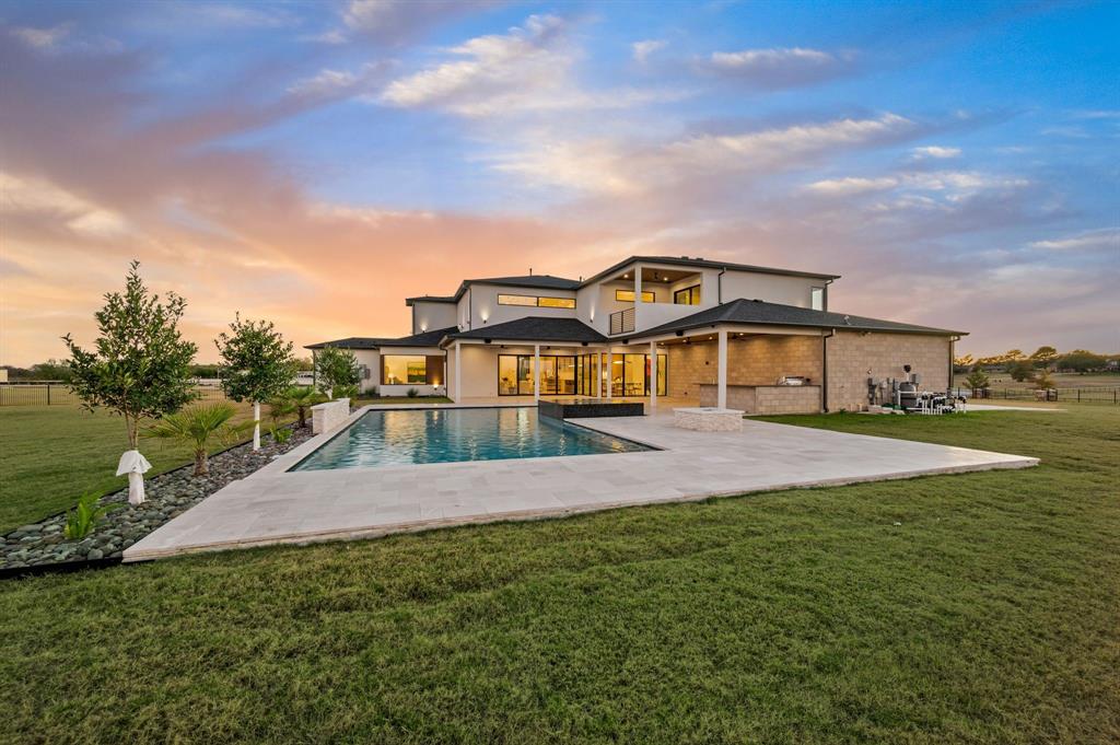 Priced to encourage strong interest - seller open to offers. Welcome to the prestigious Trifecta Estates of Bartonville. Positioned on a spacious 2-acre lot, this modern residence offers serenity, privacy, and refined contemporary design. With a seamless open floorplan, soaring ceilings, and abundant natural light from the extensive use of windows, the home brings together thoughtful architecture and effortless functionality. At the entry, a dramatic floating staircase with LED lighting establishes the tone for the home’s sophisticated aesthetic. A dedicated office provides a quiet retreat for work or study. The expansive great room brings together living, dining, and entertaining with a balanced flow. Quartz Luxury Windows by Quaker frame beautiful views of the pool area and outdoor living spaces. The chef’s kitchen is a center of craftsmanship and function. It features custom imported floor-to-ceiling cabinetry, an oversized island, and a high-performance appliance package that includes Dacor and Bosch. Additional features include a cabinet-front refrigerator, built-in coffee maker, 6-burner Thermador gas cooktop, wine fridge, ice maker, and a fully outfitted butler’s pantry with an additional sink, refrigerator, and dishwasher. The primary suite is a private retreat with a spa-inspired bathroom that includes an oversized dual shower, luxurious tub, LED adjustable lighting, and a custom walk-in closet. Upstairs, a dedicated media room opens to a balcony with views of the property. All secondary bedrooms include ensuite baths and walk-in closets. The outdoor living area is designed for year-round enjoyment and includes a covered patio with a kitchen setup. The backyard features a large grassy area, a pool and spa with a waterfall feature, and a gas firepit. Bartonville offers the peace and charm of country living with convenient access to nearby amenities, equestrian facilities, restaurants, and daily conveniences, all while maintaining a quiet and private setting.
