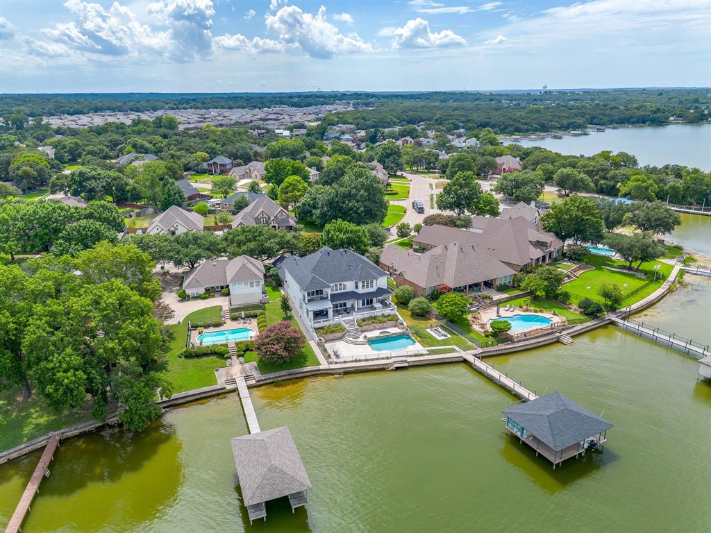 Discover lakeside luxury with this stunning waterfront home on EAGLE MOUNTAIN LAKE! Beautifully remodeled and thoughtfully designed for both relaxation and entertaining, this exceptional property features an open concept floor plan with panoramic lake views from nearly every room. The spacious main kitchen is perfect for preparing meals while enjoying the water views, while the upstairs guest kitchenette provides a convenient space for hosting family and friends! A bright sunroom and balcony invite you to relax and take in the serene surroundings. With multiple primary suites, this home offers comfort and privacy for both owners and guests. Step outside to your private backyard oasis featuring an outdoor kitchen, sparkling pool, and spa, ideal for entertaining or unwinding after a day on the lake. Boating enthusiasts will appreciate the covered boat dock and boat lift, offering immediate access to the water. Mature trees surround the property, providing both natural beauty and privacy. Inside, the home showcases numerous updates including new windows, modern light fixtures, updated baseboards, and more! Whether hosting gatherings or enjoying peaceful lakefront living, this property truly has it all! A rare opportunity to own an exceptional waterfront home on EAGLE MOUNTAIN LAKE!