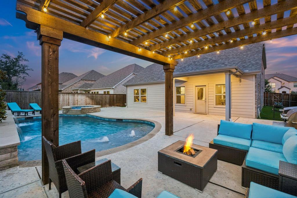 Welcome home to your own personal oasis featuring a stunning custom pool and spa with mature magnolia trees, sheer descent waterfalls, gorgeous river rock, a pergola-covered outdoor seating area, & covered patio creating the ultimate setting for summer gatherings, relaxing evenings, & year-round enjoyment. Whether entertaining outdoors or unwinding after a long day, this backyard was designed to impress. Upon arrival, stunning elevation features stone & brick edged flower beds leading to a welcoming entryway. Inside, the home showcases an open-concept layout filled with natural light, spacious living areas, rich luxury vinyl plank wood flooring & stylish finishes throughout. The kitchen is the heart of the home featuring white shaker cabinetry with black pulls, stainless steel appliances, gas range & large island perfect for gathering with family & friends. Generous living room boasts stunning floor to ceiling custom fireplace, soaring ceilings, electric fireplace, & outdoor pool views. The generously sized, light and bright primary suite offers a peaceful retreat featuring a stylish barn slider leading into a spa-inspired bath with an extended shower, dual sinks, & a custom walk-in closet. Fifth bedroom and secondary full bath downstairs is ideal for guests or dedicated office space. Upstairs features a generously sized game room, three additional bedrooms, a third full bath, & amazing storage.  Nestled in the highly sought-after Berkshire community, this beautifully designed home offers the perfect blend of modern comfort, thoughtful design, and exceptional neighborhood amenities.  Family is truly at the heart of Berkshire, where residents enjoy resort-style living with access to a community pool, fishing pond, hike and bike trails, playgrounds, parks, and more than 60 acres of open green space designed for connection and outdoor enjoyment. Located within Northwest ISD and conveniently positioned near shopping, dining, entertainment, and major commuter routes.