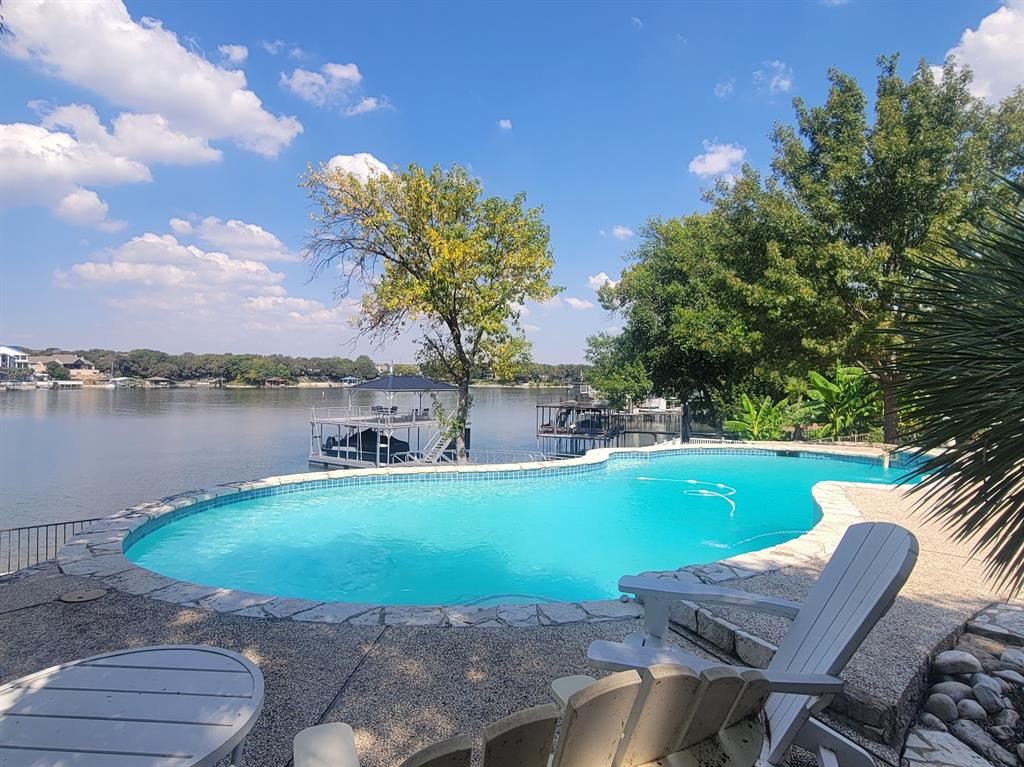 Exceptional waterfront home with contemporary design set against the stunning backdrop of Eagle Mountain Lake. Nestled in the prestigious Lake Country community. The seamless flow between living, dining and kitchen areas enhances the home's spacious feel. Featuring white oak flooring throughout home that adds warmth and elegance. Four spacious bedrooms and three full bathrooms accommodate family and guest with ease. A downstairs bedroom and living area offer the flexibility of a private mother in law suite. The gourmet kitchen is equipped with quartz countertops, solid maple cabinetry, a built in refrigerator, a propane cooktop, a wine refrigerator,  and a large center island that seats six. Upstairs you will find an airy loft space, bathed in natural light. The primary bedroom complete with large ensuite bathroom offering a stylish modern tub and double shower. Two additional bedrooms that share access to a convenient Jack and Jill bathroom. All upstairs bedrooms have access to a spacious balcony overlooking the lake, the wonderful diving pool, and the resort style backyard, creating a perfect place to relax and unwind. Home also offers 175 ft of waterfront, a gazebo and a new covered boat dock with lift that gives you private access to deep water, perfect for boating and water sports! Rare opportunity to own a piece of paradise on EAGLE MOUNTAIN LAKE! Don't miss your chance to experience lakefront luxury at its best!