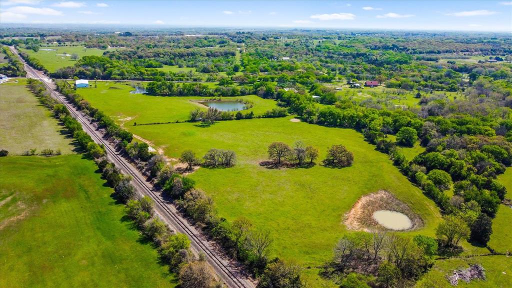 Johnson County Ag Exempted ranch property offering open pasture, four ponds, authentic log cabin living — all just minutes from Highway 67 in Cleburne, Texas. This approximately 24.99-acre tract features functional, usable land with established perimeter fencing and extensive county road frontage. Multiple gated entries allow convenient trailer access into the pasture.

Four well-positioned stock ponds — one approximately one acre in size — provide valuable water sources across the property, supporting livestock, recreation, and long-term agricultural use. Mature oak and pecan trees provide natural shade, while a seasonal creek enhances the natural landscape.

The acreage is adaptable and workable, offering flexibility for cross-fencing, arena development, hay production, or additional improvements. Whether maintaining an agricultural exemption, running livestock, or simply enjoying wide open space, the layout supports a variety of uses.

Improvements include a genuine 3-bedroom, 2-bath log cabin constructed with true log exterior and a durable metal roof designed for Texas conditions. The home is comfortable and fully functional, offering authentic cabin character with opportunity for personalization over time.

Additional structures include a detached two-car garage with matching log construction and a large metal storage building with high ceilings and enclosed storage space for equipment, hay, or feed. Enjoy open skies and rural privacy while remaining within commuting distance of Fort Worth via Highway 67 and the Chisholm Trail Parkway.