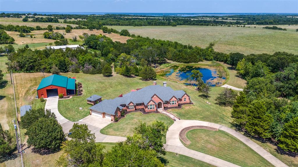 Don't miss out on this Stunning Custom Home with panoramic views of the Pool, Pond, and Fountain from the living room,Primary Suite, and Bath!  Move-in ready with open layout, abundant natural light, and gourmet kitchen featuring granite countertops, Viking 6-burner gas cooktop, double oven, walk-in pantry, triple sinks, warming drawer, and more. Luxurious primary suite includes oversized walk-in custom closet. This Home features 3BR,3.5Bath home has mother in law suite and Surround sound and large-screen TV setup make it perfect for entertaining or relaxing. Property is in pristine condition with its beautiful finish out. It includes a water well with filtration, softener system, 3-car garage with natural light workshop, and 12’x30’ barn for storage or tools with electricity. Store your BOAT, RV, ATVs in the New 2,400 sq ft party barn with 16ft door (2023) with 3 beds, full kitchen, 1 full and 2 half baths all with HVAC and Large Front porch. Electric gated entry with brick-stone columns and seasonal landscaping. Perfect for a residence, lake house, and Airbnb! 6 Minutes from Lake Texoma and Marinas! Currently Working on getting Ag Exemption