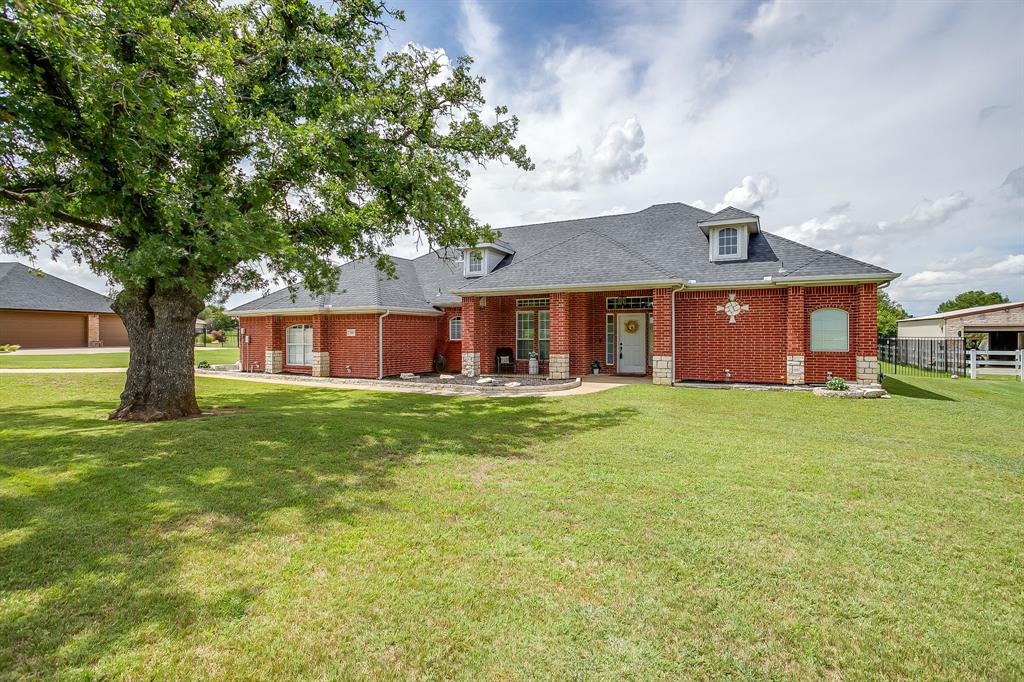 Welcome to the home of you and your significant other's dreams! A place where you can relax, entertain and simply enjoy! From the moment you pull up, you will appreciate the massive front covered porch, iconic red brick and Austin stone exterior, and the perfect pallet to customize landscaping. The mature shade trees add a special touch. With added updates like HVAC in 24, gas HWH in 22, Outdoor kitchen addition in 23, extended back patio and custom she-closet in 21, roof in 22 and many more added upgrades; this property is hard to beat! Did I mention it is VA Assumable at 2.75%!! All of this and a 30 x 40 insulated shop, AC cooled, bathroom and drive through capability; you really have to see to believe! Once inside, the rich wood laminate flooring flows through the flawless floor plan welcoming you to the great room. Here, envision a formal dining and sitting space or the ultimate game room for a pool table. On to the massive primary suite where you will find not only HIS walk-in closet, but a custom SHE closet complete with space for long dresses, shoes, purses and MORE! The ensuite has dual vanities as well as a huge walk-in shower. Flowing onto the other part of the home, you will find an exceptional office space or craft room, a culinary delight for a kitchen complete with two ovens; one gas and one electric, farm sink, walk-in pantry, tons of cabinets and countertop workspace. Enjoy breakfast in the beautiful, bayed breakfast nook or at the bar. All this overlooking the gorgeous backyard and spilling over into the family room. Cold nights? Snuggle up by the fireplace! Split living allows the secondary bedrooms and Jack and Jill bath to be enjoyed by littles or guests with privacy. Both rooms showcase large closet space, tall ceilings and fans. Decorative lighting throughout adds a decorative touch, updated windows and electrical add piece of mind. Schedule to see for yourself, today, before this one gets away!
