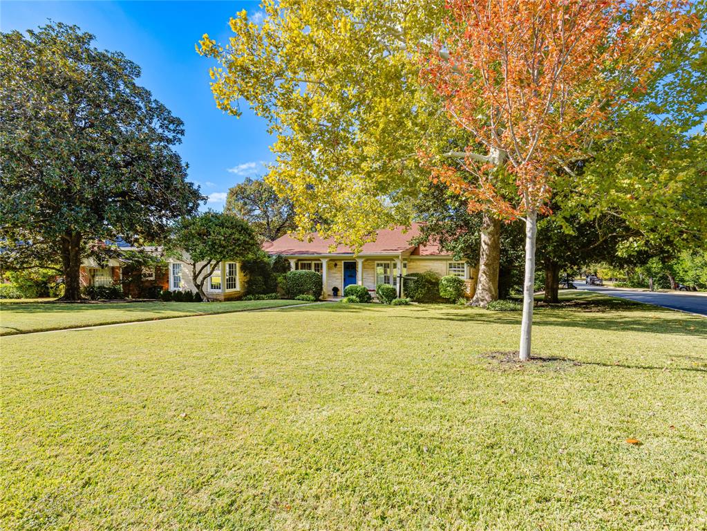 Charming Austin limestone home on a corner lot in the heart of the TCU, Colonial area, surrounded by mature trees and green space with minimal concrete and a true neighborhood feel. The striking exterior, with its red roof and blue front door, sets the tone for a home full of character, natural light, and thoughtful design. Inside, the layout offers spacious common living areas with private rooms positioned on either side, creating a functional and comfortable flow. Large windows throughout the home provide abundant natural light and views from nearly every room, with a standout wall of windows in the sunroom and secondary living space. The living area is anchored by a beautiful freestanding limestone gas fireplace, creating a warm yet open environment. The kitchen is efficient and well-designed with ample storage, multiple prep areas, and a corner sink overlooking the neighborhood. Outdoor living is a highlight, featuring three separate sitting areas including a front porch, elevated back deck, and lower patio, all offering unique views and a seamless connection to the surrounding greenery. The backyard provides a rare balance of privacy and openness, ideal for both relaxing and entertaining.  Additional features include a side driveway with turnaround access onto Park Hill, under-home storage, and a yard well-suited for pets and outdoor enjoyment. Located just minutes from TCU and Colonial Country Club, this home offers a vibrant yet peaceful setting with convenient access and strong neighborhood appeal.