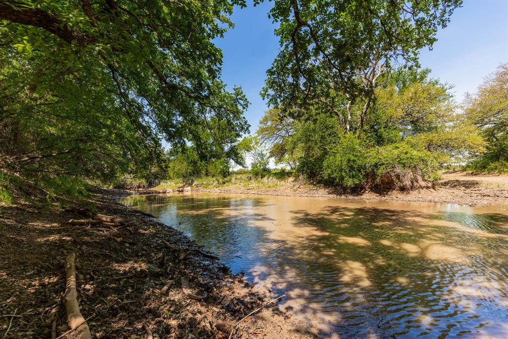 1,055 +- acres of rolling, scenic Texas land, this ranch combines exceptional water, diverse terrain, and well-planned improvements to create a premier cattle and recreational property.  Nearly three miles of Mud Creek wind through the ranch, with massive Oak and Elm trees lining the banks and creating a stunning natural corridor that supports wildlife, livestock, and year-round beauty!  Lost Creek Ranch is thoughtfully balanced for productivity and recreation, featuring 75 +- acres in cultivation, 300 +- acres of improved pasture, and 680 +- acres of native brush.  This mix provides excellent grazing capacity while preserving prime habitat for wildlife.  With 14 stock tanks scattered across the ranch, water is abundant and well distributed.  For the sportsman, the property offers incredible deer, dove, turkey, quail, & hog hunting, supported by the creek, heavy timber, and varied cover.  For the cattleman, the ranch includes a true working set of pens designed for efficiency, along with a huge shed for equipment storage and operations.  Improvements include a comfortable two bedroom, one bath barn dominium, ideal for a weekend retreat, ranch headquarters, or guest lodging.  Multiple hilltop vantage points offer panoramic views and potential homesites.  This is a rare opportunity to own a legacy ranch with strong agricultural value, outstanding hunting, and the natural character that makes a property unforgettable!