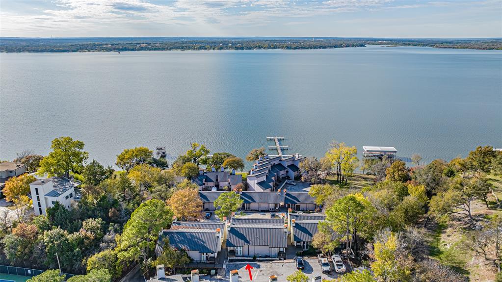 Welcome to lake life at Chart House Condominiums. This gorgeous, light-filled condo can be your new lake-view retreat or a comfortable full-time home. The two-story floor plan features a fully renovated interior with Pergo flooring, granite countertops, fresh paint throughout, custom cabinetry, generous storage, all-new windows and doors, and two private bedrooms with en-suite bathrooms located on the lower level. Upstairs, the main living area offers vaulted ceilings, an open-concept kitchen, a powder room, and a separate laundry room. The refrigerator and washer-dryer are included. Step outside to two brand-new decks, accessible from both levels, perfect for morning coffee or evening sunsets over the lake. The gated community provides an assigned parking space, two daytime-use docks, lakeside picnic tables with seating and grills, plus a dedicated storage area. The exterior is currently being renovated by the HOA. HOA fees cover water, trash, sewer, exterior insurance, and internet—meaning the only remaining utility bill is electric. Don’t miss your chance to own the perfect lake-view condo and embrace the laid-back lifestyle at Chart House.