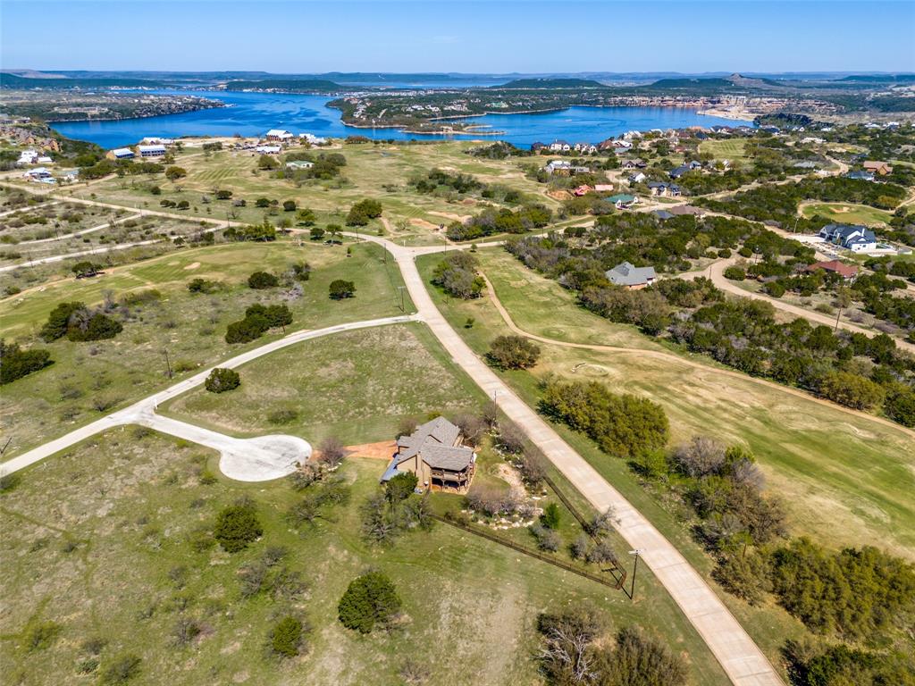 Luxury, privacy, and endless recreation await at this stunning custom home nestled within the prestigious gated community of The Cliffs Resort on Possum Kingdom Lake. This inviting 3-bedroom, 3-full-bathroom property proves to be an absolute entertainer’s paradise. The meticulously designed open floor plan immediately draws you in, featuring massive, strategically placed windows that flood the living spaces with abundant natural light and frame the picturesque surroundings. The warmth of the interior is anchored by exquisite custom cabinetry that adorns every corner. Every detail has been thoughtfully curated to balance grand-scale entertaining with comfortable, everyday living. A premium, integrated surround sound system flows seamlessly from the spacious main living area straight out to the expansive back balcony, creating an immersive, mood-setting audio experience for your guests. Step down into the fully fenced backyard to discover your own secure, private oasis. This generous outdoor living space is a true extension of the home, coming completely equipped with a high-end outdoor kitchen, extensive bar seating, and a dedicated outdoor TV space perfect for game days. Effortless lake living is guaranteed thanks to brilliant, practical touches like a built-in dumbwaiter, making unloading groceries, luggage, or boating gear an absolute breeze. The rare luxury of dual laundry rooms—one conveniently located on each level ensures that managing wet lake towels and guest linens is incredibly easy. Yet, the incredible perks of this property certainly don't stop at your front door. You can easily access the full-service marina for lake days, an acclaimed 18-hole Championship golf course brilliantly designed by Robert Von Hagge. Visit the On-site spa, multiple resort-style swimming pools or the Chaparral Grille without ever having to leave the neighborhood. Backed by the peace of mind of 24 7 manned security, this is lake resort living at its absolute finest.
