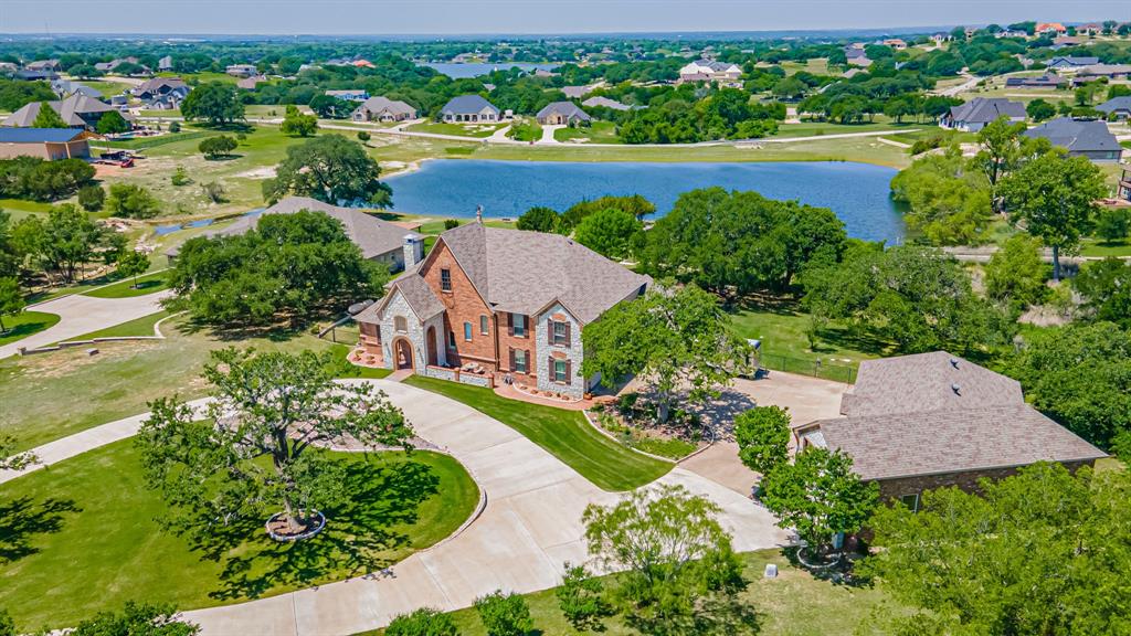 Set apart by thoughtful design and elevated finishes, this stunning custom home offers a seamless blend of comfort, space and standout features.  Inside, you'll find two spacious living areas perfect for both everyday living and entertaining. The layout is ideal, with a private upstairs retreat featuring three bedrooms, an additional living space and kitchenette as well as a balcony overlooking the pool and pond. The primary suite is a true sanctuary, complete with a beautiful solarium sitting room that invites natural light and provides the perfect spot for morning coffee or winding down in the evening.  Step outside and experience resort-style living at its finest.  A custom pool and hot tub anchors the outdoor space, complemented by a cozy outdoor fireplace- ideal for year-round enjoyment and hosting unforgettable evenings under the stars. The property also boasts peaceful views of a pond, adding to the serene, private setting.  For those needing extra space for hobbies or travel, the separate 45' RV garage with an attached workshop is a rare and valuable feature, and a heated and cooled dog room with access to the yard. Comes with a deeded boat slip at marina.  This home is the perfect combination of luxury, practicality and lifestyle designed for those who want it all. Well strictly for irrigation. Comes with boat slip E23