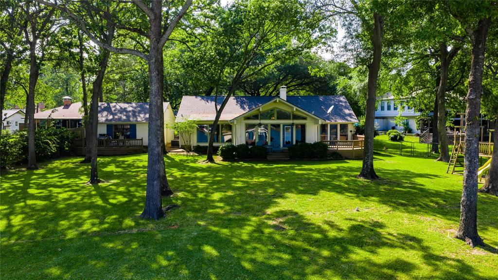 Spacious waterfront home offering two living areas, three bedrooms, and three full baths, plus a two-car garage. The open-concept design features high vaulted ceilings and a brick fireplace creating a warm and expansive feel. A versatile flex room provides the option for a fourth sleeping area, perfect for accommodating guests. Situated on one and a half lots with 158 ft of shoreline, the property showcases a beautiful setting with mature trees and a sweeping views across a large bay. Enjoy outdoor living on the covered porch or separate deck, along with a sandy swimming area perfect for lakeside fun. A private boathouse with sundeck completes this exceptional waterfront retreat.