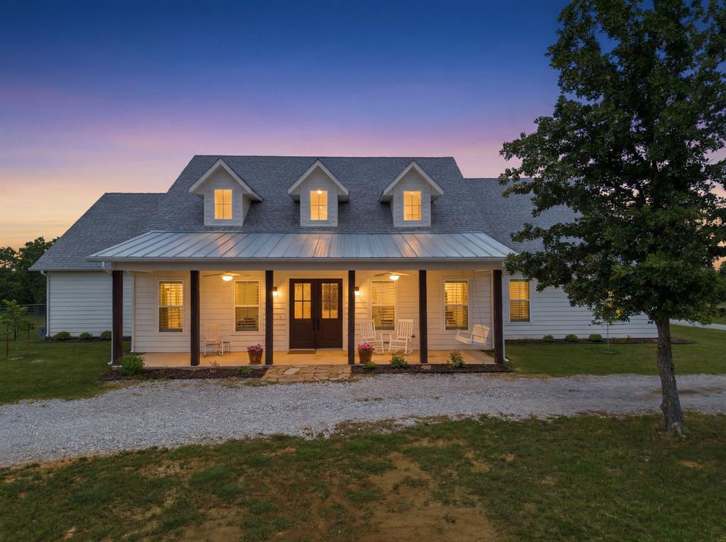 Perched atop a scenic hill on 4+ acres, this custom home offers sweeping eastern views, excellent drainage, and a beautiful mix of open pasture and mature oak trees, making it ideal for horses and outdoor living. Located near the LBJ National Grasslands, residents enjoy convenient access to miles of hiking and biking trails, plus two neighborhood fishing ponds reserved for residents.

Built with comfort and efficiency in mind, the home features spray foam insulation, two high-efficiency Daikin heat pumps, insulated garage doors, a Generac whole-home automatic generator, well water with UV purification, water softener, and reverse osmosis systems for premium drinking water.

The chef's kitchen boasts a large island, double ovens, coffee bar, walk-in pantry, butler's pantry, and abundant under-cabinet lighting. The living area is anchored by a stunning floor-to-ceiling limestone fireplace with a Mendota gas insert and thermostat-controlled operation.

The spacious primary suite includes a luxurious bath and oversized custom closet with direct access to the laundry room. Throughout the home you'll find engineered hardwood and travertine flooring, solid wood interior doors, 10-foot ceilings, plantation shutters, tilt-in windows, beadboard accents, and custom vanities.

Relax on the covered front porch with swing and ceiling fans, or enjoy the expansive back porch featuring a wood-burning fireplace, hot tub hookup, and peaceful valley views where deer and wildlife are frequent visitors. The fully fenced backyard includes pipe fencing, multiple gates, and a full irrigation system.

An unfinished second floor with dormer windows provides extensive storage and future expansion potential. Additional features include a tankless water heater, 500-gallon propane tank, circular drive, ample parking, and an underground septic system. This exceptional property combines modern convenience, energy efficiency, and the tranquility of country living.