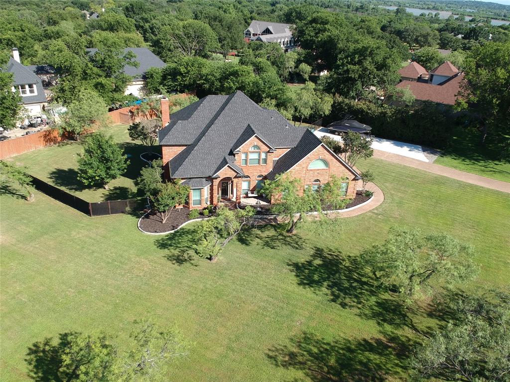 $15K Price Adjustment on this 1 Acre lot in Flower Mound
Welcome to an exceptional luxury estate perfectly positioned on a sprawling 1.1-acre lot in Flower Mound’s highly coveted Vineyard subdivision. Masterfully updated traditional brick home beautifully pairs timeless elegance with modern sophistication.  Pass through the grand foyer, flanked by formal living and dining rooms, to find rich hand-scraped hardwood floors guiding you into a main living room. This central space is anchored by a brick fireplace and framed by floor-to-ceiling windows showcasing views of your private backyard paradise. Ideal for remote professionals, the main level features two dedicated workspaces: a private home office with elegant French doors, and a massive 23x8 climate-controlled workshop secondary office attached to the back-facing garage.  The kitchen is a chef’s dream, meticulously updated with custom cabinetry, granite countertops, a central island, and ambient lighting. Culinary features include a gas cooktop, double ovens, a custom vent hood, a built-in wine cooler, a walk-in pantry, and dual sinks, featuring a classic farm sink.  A dual staircase leads to 4 bedrooms. 2 of the bedrooms have ensuite bathrooms and all have walk in closets.  The primary suite serves as a true retreat, offering a sitting area and a private covered balcony for peaceful evenings. The primary bath features his & her sinks, a garden soaking tub, a separate shower, and a custom closet complete with a laundry chute and a hidden door leading to expansive attic storage.  Step outside to a resort-style backyard oasis on a level, beautifully landscaped interior lot. Unwind on the expansive covered patio and deck, or float the evening away in the sparkling, in-ground pool and spa combo.