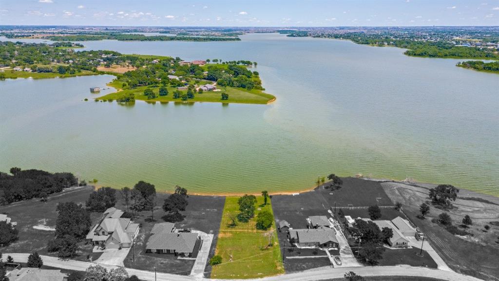 Rare opportunity to secure premium lakefront land on Lewisville Lake in Little Elm. This approximately 0.40-acre waterfront parcel offers direct water access, panoramic open-water views, and exceptional flexibility with no HOA restrictions. For the luxury buyer, this property presents the perfect canvas to design and build a custom dream home with breathtaking sunset views, private shoreline access, and the ability to install a portable boat ramp for effortless lake living. Enjoy kayaking, paddleboarding, fishing, and boating directly from your own backyard while remaining minutes from dining, entertainment, and the vibrant Little Elm waterfront district. For builders and investors, this parcel represents a rare and increasingly scarce North Texas waterfront asset. With limited remaining lakefront inventory in the area, strong buyer demand for custom homes, and proximity to Frisco, Plano, and major corporate corridors, the property offers compelling upside potential. Ideal for a luxury spec build, high-end resale, or long-term hold in a growing lakeside market. The gentle slope toward the shoreline enhances build potential while maximizing view corridors and outdoor living design options. Waterfront land continues to be one of the most desirable and resilient asset classes in North Texas real estate.
Build a signature estate or develop a premier spec home. Or secure and hold a tangible waterfront investment. Nestled in a quiet area yet just minutes from all the fun Little Elm has to offer — including the lakefront swim beach, marina, restaurants, and parks. Enjoy the best of both worlds with a convenient commute: 35 minutes to DFW Airport and 45 minutes to Dallas. Lakefront lots like this are few and far between and becoming rarer.