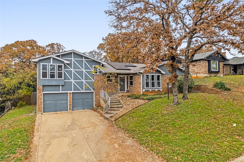 Welcome home to this charming split-level residence located in the established Carol Oaks neighborhood, celebrated for its mature trees, timeless character, and welcoming, family-friendly feel. Thoughtfully updated with brand new windows throughout, this light-filled home offers multiple living areas that provide flexibility for both everyday living and effortless entertaining.

The main level showcases a spacious living room anchored by a classic brick, wood-burning fireplace and complemented by stylish luxury plank vinyl flooring. The inviting eat-in galley kitchen features butcher block countertops and a tile backsplash, blending warmth, functionality, and timeless design.

The generously sized primary suite offers a private retreat complete with an ensuite bathroom featuring a walk-in shower, a walk-in closet with custom shelving, and a private balcony overlooking the backyard. A secondary bedroom includes an Elfa closet system for smart organization, while the full hallway bathroom offers built-in cabinetry for added storage. The converted garage provides additional versatile space ideal for a home office, gym, or playroom.

Step outside to the expansive, fully fenced backyard with an oversized, multi-tiered deck—perfect for outdoor gatherings, relaxing evenings, or play.

Ideally located, this home provides convenient access to local shops, parks, schools, and major highways. Downtown Fort Worth and the vibrant Magnolia District are just a 10-minute drive away, with AT&T Stadium and Globe Life Park only a few miles from your doorstep. This home truly blends comfort, character, and an exceptional location.