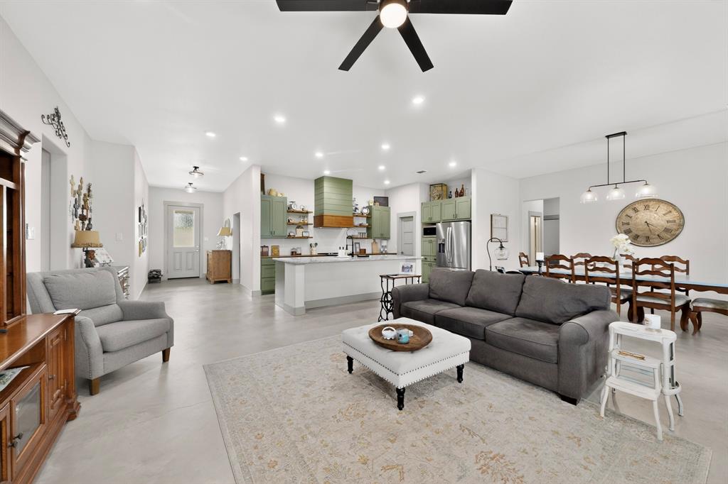 Welcome to this stunning 2024-built barndominium where modern design meets country living on a full acre—offering space, style, and functionality just minutes from Sherman and the new Texas Instruments campus. This thoughtfully designed home features 4 bedrooms, 3 bathrooms, and a dedicated study, all finished with durable concrete floors throughout for a sleek, low-maintenance lifestyle. The open-concept layout is anchored by a chef-inspired kitchen showcasing granite countertops, an oversized island, a deep granite sink, soft-close cabinetry, and an extra-large walk-in pantry—perfect for both everyday living and entertaining. The primary suite is a true retreat, featuring luxurious quartzite countertops, an oversized walk-in shower with dual shower heads and sitting bench, and a unique private door leading directly to the outdoor dog run—blending convenience with thoughtful design. Secondary bathrooms elevate comfort with marble countertops and spray foam-insulated tubs designed to keep water hot for up to 2 hours. The layout was thoughtfully designed for multigenerational living with the front wing being able to be closed off for an in-law suite.
Step outside to enjoy the covered back patio, accessible from both the living area and garage, where you can unwind and take in breathtaking sunset views overlooking your private acre with a dry pond. Additional highlights include built-in blinds in exterior doors, an aerobic septic system, and electrical and secondary plumbing line run for future outbuilding. Car enthusiasts and tech-forward buyers will appreciate the oversized 2-car garage with 9-foot wide doors, pre-wired for an electric vehicle, and ample storage throughout—including walk-in closets in secondary bedrooms. This property delivers the perfect balance of modern comfort, thoughtful upgrades, and peaceful outdoor living—all in a prime location with convenient access to major growth and development. The home will include a zero turn riding lawn mower.