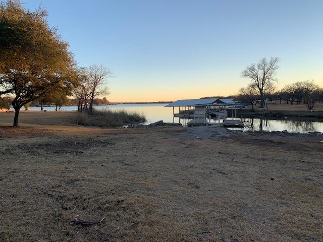 OCCUPIED & LEASED FOR $1,500 PER MONTH UNTIL END OF MAY 2026. Buy and have an immediate income producer.  Enjoy the south breeze and shade from your big oak trees and covered deck at this lakefront 3 bed, 2 bath, all while overlooking your own single slip covered boat dock.  Park your toys in the double car garage or under the carport.  Kids coming in town??? Put them in the huge back room with its own entrance.  Leased lot has approximately 37 years left and is currently a mere $360 per year, BUT...OWNERS OF LOT WILL SUPPOSEDLY SELL.  If you were able to purchase the lot from the 3rd party, this should become able to finance.  A chain link dog kennel, 1 storage building, and a screened-in workbench area are also present for your projects.  You will not be able to get conventional financing, unless you buy-out the lease lot.  Call for details.