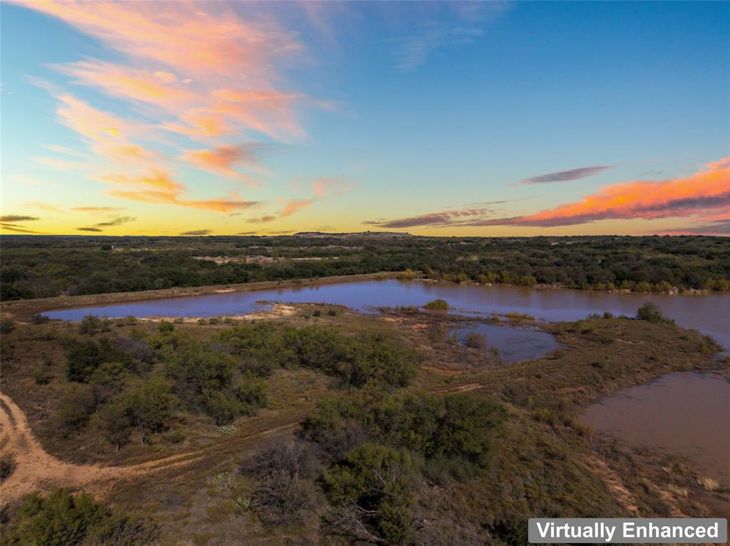 187.79 acres with 20+ acre lake and dam. Paved county road frontage with power and water. Roads into and throughout the fenced property. No restrictions. Ag exemption currently in place. Beautiful trees and rolling hills throughout. Could be hunting property, great ranch compound, or a terrific spot for your showcase home. Minerals do not convey. Photos and video of lake are after a heavy rain. Video and 3D tour links are attached.