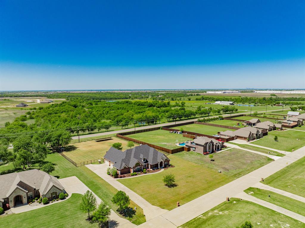 Meticulously maintained home in Forney on just over one acre, offering space, functionality, and thoughtful upgrades throughout. With 11-foot ceilings and spacious rooms, this home is designed for both comfortable living and effortless entertaining. The open-concept layout features a large living area with a wood-burning fireplace and luxury vinyl plank flooring throughout—no carpet. The remodeled kitchen serves as the heart of the home, showcasing quartz countertops, soft-close cabinetry and drawers, a beautiful custom vent hood, pot filler, 5-burner gas range, and all new appliances. A reverse osmosis water filtration system adds convenience and quality. A 500-gallon propane tank services the home, including the outdoor grill, and is already plumbed for a future generator. The primary suite offers a private retreat with a garden tub, separate shower, and an oversized walk-in closet with direct access to the laundry room. Two secondary bedrooms share a Jack and Jill bath, while a fourth bedroom near a full bath is ideal for guests. Upstairs provides exceptional flexibility with a media room, home office, additional flex space perfect for a gym or second office, a half bath, and a wet bar. Step outside to a backyard designed for relaxation and entertaining, complete with a saltwater pool, spa, waterfall feature, outdoor kitchen, cabana, and covered patio surrounded by landscaped grounds. Additional highlights include air curtains on exterior doors, fully paid-off solar panels that convey at closing, and a 4-car garage with extra-deep bays for larger vehicles or added storage.