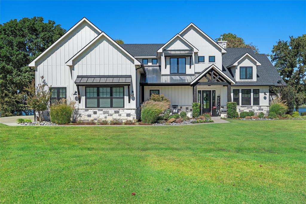 Welcome to your lakefront retreat in the exclusive gated community of The Shores. Set on over an acre with 177 feet of shoreline in a protected cove, this property offers deep water at your private dock—perfect for boating, watersports, or peaceful views.
Outdoor living shines with a covered patio featuring motorized screens, built-in gas grill, granite counters, and refrigerator. Mature shade trees, a fire pit, and beautifully maintained grounds with a lake-fed sprinkler system create a relaxing, resort-style setting.
Inside, the open-concept design is ideal for entertaining. The chef’s kitchen includes Bosch appliances, quartz countertops, gas cooktop, double ovens, microwave, and a large island with bar seating. The kitchen flows seamlessly into the dining and living areas, where expansive sliding windows frame stunning lake views and open to the patio.
The billiards room offers a reclaimed wood ceiling, full wet bar, and stylish finishes. The oversized primary suite is a private escape with lake views, vaulted wood-beamed ceiling, and French doors to the patio. The spa-like bath features designer tile, soaking tub, large double-head shower, dual vanities, and separate walk-in closets—including a custom closet with chandelier.
Upstairs, a guest wing provides unique bedrooms plus a bunk room with four built-in full-size beds and a private living area—perfect for guests or a bonus space. The home comfortably sleeps 12–16.
Additional features include an oversized three-car garage with workshop, whole-house water filtration, and insect misting system.
Just 1 hour 15 minutes from Dallas, this is lake living at its finest.