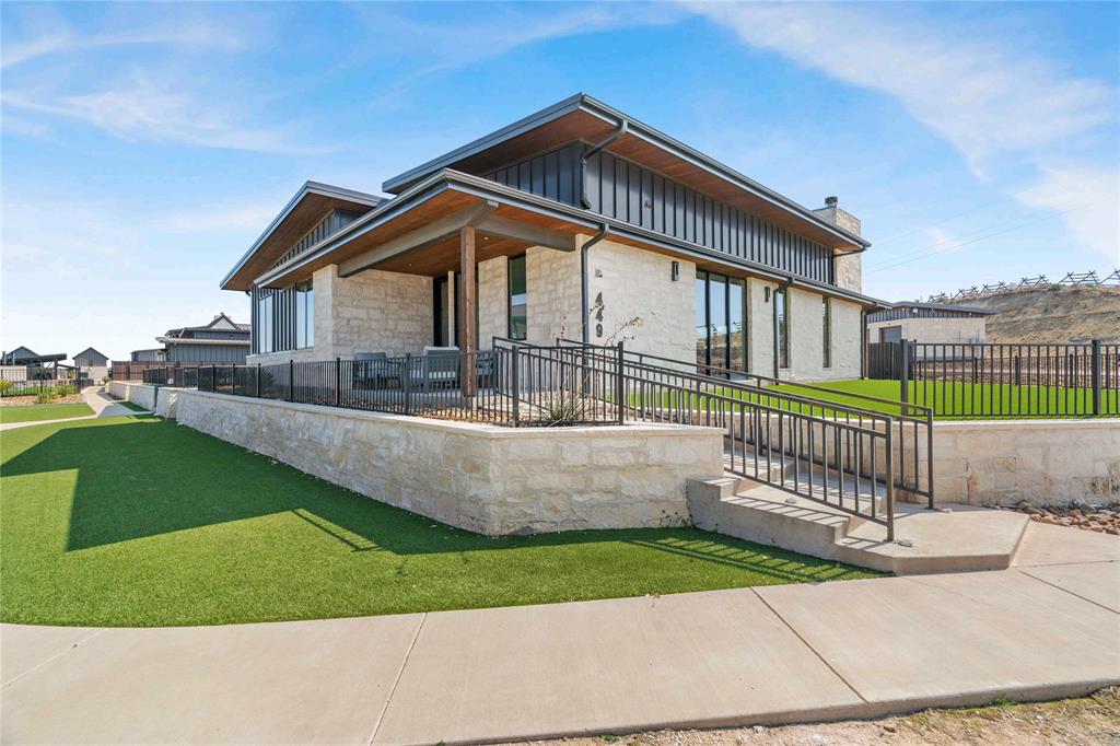 449 Emma Jean Trail is a beautifully appointed single-level residence within the exclusive, gated community of Rough Creek Lodge and Resort, offering 2,178 square feet of refined Hill Country living across 3 bedrooms and 3 full bathrooms. Buff limestone masonry, dark standing-seam metal roofing, and floor-to-ceiling glass create a striking modern exterior. Inside, soaring shiplap ceilings, wide-plank hardwood floors, and an open-concept layout set the tone for effortless entertaining. The chef's kitchen features a Sub-Zero refrigerator and professional Wolf range, paired with bold cobalt-blue cabinetry, white uppers, gold hardware, and a quartz waterfall island. A custom brass bar wall anchors the dining area, and the living space flows naturally to the covered patio, complete with an outdoor fireplace and mounted TV for year-round use. Two main bedrooms each with their own en suite bath, plus a custom bunk room featuring queen-over-twin bunks and a shared hallway bath. The lot is one of the community's largest private green spaces, connecting directly to the pickleball court. Ownership at Rough Creek unlocks 9,000 gated acres of Texas Hill Country adventure, including private fishing lakes, owner-only experiences, guided bird hunts, Beretta Room privileges, zip line, climbing wall, horseback riding, sporting clays, a 1,000-yard rifle range, award-winning dining, wellness services including massages and facials, and a supervised Kids' Ranch. Concierge-level HOA services and full-time on-site support make ownership as effortless as it is extraordinary. Home sold fully furnished, minus artwork and personal items. Two new-condition Polaris Rangers available separately, making this property completely turn-key on closing day.