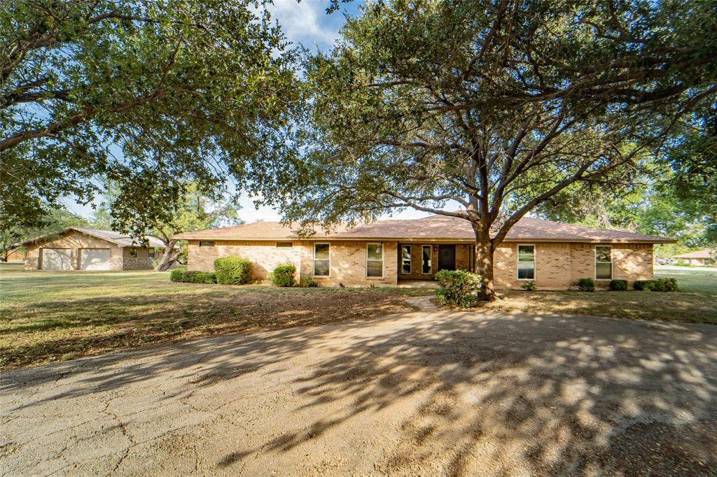 Welcome home to your own private retreat in Breckenridge — a timeless Texas classic-style brick home with a sparkling pool, shaded by mature trees, tucked away on a peaceful cul-de-sac. Set on 1.3 acres, this 3-bedroom, 3-bath beauty has the perfect mix of classic charm and modern comfort. Step inside and you’ll instantly feel how open and inviting it is — warm wood floors, natural light pouring through the windows, and a cozy stone fireplace that just calls for quiet evenings in. The kitchen is the heart of the home, with custom cabinets, granite counters, double ovens, gas cooktop, and a big island where everyone naturally gathers. There’s room for everyone here — two living spaces for movie nights, game days, or a home office. The primary suite feels like a true getaway, with space for a sitting area, private doors that open to the patio and pool, and a spa-inspired bath featuring dual vanities, soaking tub, walk-in shower, and huge closet.  Outside, the backyard feels like your own resort — a sparkling pool, large patio for outdoor dining, and room to garden or play under the shade trees. There’s even a circle drive and a detached garage with workshop space for hobbies or storage.  Located just minutes from Hubbard Creek Lake, Breckenridge Country Club, shopping, and schools — and only a short drive to Abilene or Fort Worth — this home offers the perfect blend of small-town peace and modern convenience. If you’ve been dreaming of a place that feels like “home” the moment you pull up — this is it! Call today to unlock your next chapter!