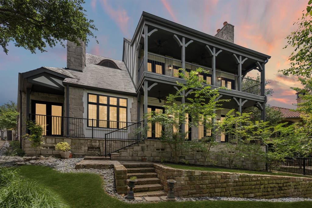 Nestled within the guard-gated Enclave at Windsor Ridge, this exceptional Tudor Revival estate offers timeless architecture, outstanding craftsmanship, and greenbelt views. Designed by architect Paul Haberman and custom built by Jim Sexton Homes, this engineered pier-and-beam residence showcases rich alder wood cabinetry, crown moldings, ceiling beams, custom built-ins, and architectural details throughout. A dramatic two-story foyer welcomes you with terracotta flooring, a beamed ceiling, iron staircase, and statement chandelier. The chef’s kitchen is designed for everyday living and entertaining, featuring alder wood cabinetry, granite countertops, a large center island, walk-through pantry, and Viking, Sub-Zero, and Bosch appliances. A formal dining room offers a beamed ceiling, bay windows with custom shutters, and a butler’s pantry with gothic-arched glass cabinetry. Anchored by a floor to ceiling stone fireplace, the expansive family room features hardwood floors, exposed beams, and French doors opening to a covered balcony overlooking greenbelt scenery. A sophisticated study with custom built-ins and a fireplace provides the perfect home office or library. The first-floor primary suite is a private retreat with a sitting area and outdoor patio. The spa-inspired bath features marble finishes, dual vanities, an oversized shower, a custom closet with built-ins, and a private laundry area adds convenience. Upstairs, two spacious guest suites offer ensuite baths and natural light. The oversized game room is ideal for entertaining with a fireplace, wet bar, refrigerator, flexible media space, and balcony access with treetop views. Additional highlights include an oversized three-car garage with Tesla charger, and you are just a golf cart ride away from The Ritz-Carlton Las Colinas & The Nelson Golf & Sports Club. This residence combines architectural distinction, luxury finishes, and exceptional functionality in one of the area's most exclusive communities.