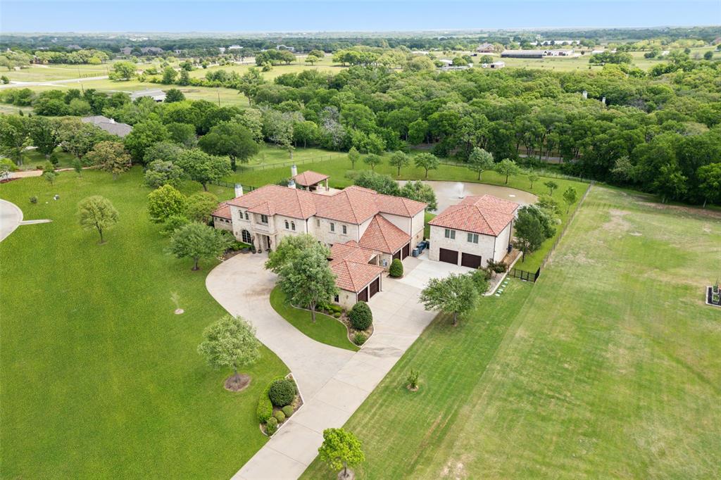 Stunning, stately, and sprawling—this extraordinary custom estate perched on a private 3-acre lot is impressive in every way. Built with exceptional attention to design, luxury, and craftsmanship, it features exquisite architectural details including rich crown molding, coffered ceilings, custom built-ins, plantation shutters, and natural stone countertops in both the kitchen and bathrooms. The curb appeal is unmatched with a handsome stone façade, Spanish tile roof, and double-door entry that opens to an elegant foyer and sweeping grand staircase. A formal dining room with a striking chandelier sets the stage for unforgettable gatherings, while the office features a cozy stone fireplace and built-ins. The gourmet kitchen is truly a chef's dream and has a large island, a built-in Sub-Zero Refrigerator, plus a separate built-in freezer. The kitchen is open to an expansive living room with vaulted wood beam ceilings, a stone fireplace & a wall of windows that fill the home with natural light. The floorplan flows effortlessly, with all 5 bedrooms offering ensuite baths and walk-in closets, 5 full baths and 3 half-baths.  Ideal for guests or multigenerational living, both the primary suite and a secondary suite are located on the main floor. The luxurious primary retreat includes a sitting area, spa-like bath, and a massive walk-in closet. Upstairs offers a large billiard room and a media room with custom built-ins & a large wet bar. The grounds are both beautiful and functional, featuring a stunning pool, cabana, and a detached garage-workshop with over 3,000 sq ft, HVAC and water. 673 sq ft AC shop as well as 1,493 sq ft of AC finished out attic space. Truly a one-of-a-kind opportunity for luxury living!