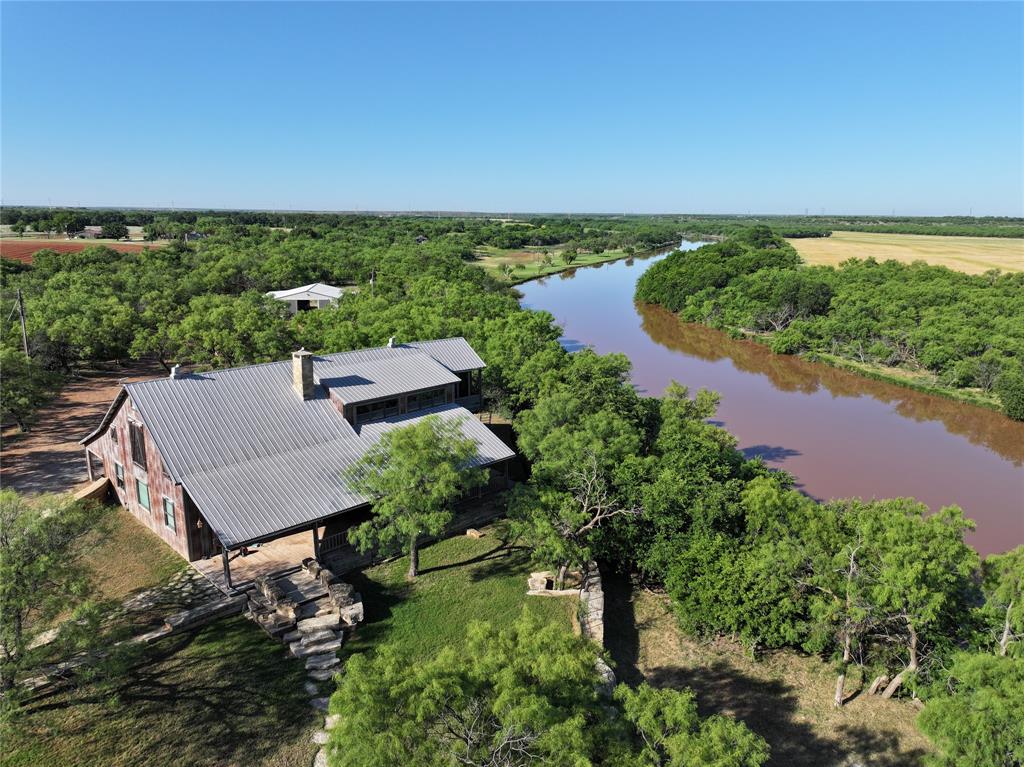 Experience one of the most unique riverfront ranch properties in West Texas with this remarkable 117.52 acre estate featuring over 5,000 feet—nearly a full mile—of river frontage. With the river stretching approximately 200 feet wide throughout much of the property, opportunities like this are exceptionally rare.

The custom-built 3,017 square foot home offers 4 bedrooms and 2.5 bathrooms with outstanding craftsmanship throughout. Massive wood beams, custom finishes, and expansive windows create a warm yet impressive atmosphere while showcasing stunning views of both the river and the large stocked pond. The open-concept layout includes a spacious living area, large eat-in kitchen with high-end appliances, and multiple outdoor entertaining spaces including front and back porches plus a screened-in upstairs porch overlooking the river.

The stocked pond behind the home is loaded with bass, crappie, drum, and catfish while also providing irrigation for the beautifully maintained lawn. Wildlife is abundant, including deer, hogs, turkey, quail, ducks, and bobcat, making this an outstanding recreational property.

Additional improvements include a private boat dock on the river, a fishing pier with cabin overlooking the water, a massive decorative rock wall fence, a 30x100 enclosed shop with concrete floors and electricity, and two horse barns. The larger barn measures approximately 70x120, while the second 36x48 barn includes horse stalls and outdoor runs.

Whether you're seeking luxury living, world-class hunting and fishing, an equestrian property, or a legacy ranch to pass down for generations, this exceptional riverfront estate delivers a rare combination of beauty, recreation, and functionality.

{Information believed accurate but not guaranteed. Property sold “as is.” Acreage, maps & fence lines are approximate. Buyers should verify details. Subject to errors, changes, prior sale, or withdrawal.}