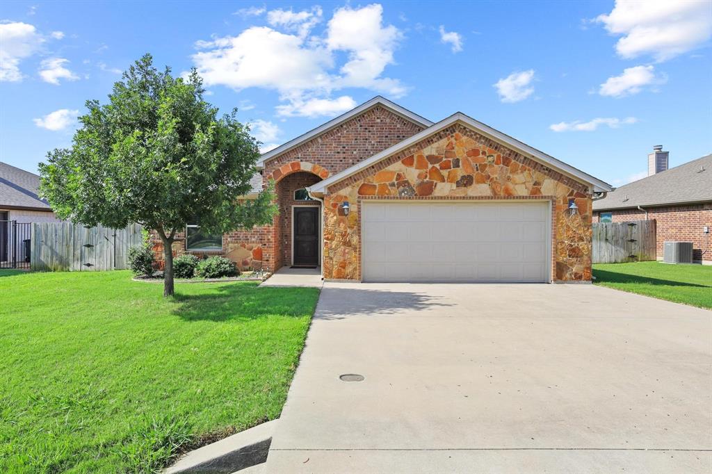Welcome to this beautifully maintained brick and stone home in the highly desirable Tioga ISD. Built in 2016 and situated on a spacious lot in Old Turner Ranch Addition, this move in ready home offers 3 bedrooms, 2 full bathrooms, and 1689 square feet of thoughtfully designed living space. The open concept floor plan creates a seamless flow between the living room, dining area, and kitchen, making it ideal for both everyday living and entertaining. The spacious living room features a stunning stone wood burning fireplace and abundant natural light. The kitchen is equipped with granite countertops, rich wood cabinetry, stainless steel appliances, a breakfast bar, pantry, and ample workspace for cooking and gathering. The private primary suite is split from the secondary bedrooms and offers a relaxing retreat with a large bedroom, oversized walk in closet, garden tub, separate shower, dual sinks, and generous storage. Two additional bedrooms and a full bath provide flexibility for family, guests, or a home office. Durable wood look flooring extends through the main living areas while the bedrooms offer comfortable carpeting. Step outside to enjoy the covered back patio overlooking a large fenced backyard with plenty of room for play, pets, gardening, or future outdoor enhancements. A storage building provides additional space for tools and equipment. Additional features include a two car garage, sprinkler system, rain gutters, ceiling fans, security system, city water, and city sewer. Conveniently located with easy access to major highways while maintaining the charm and small town atmosphere that makes Tioga so popular. This property offers the perfect combination of comfort, functionality, and location. Come experience all that this exceptional home has to offer.