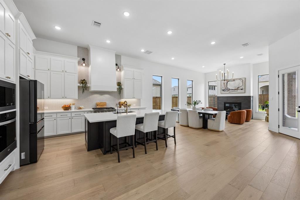 Luxury meets modern elegance in this stunning north-facing one-story Tradition Homes ranch in highly sought-after Prosper ISD! Built in 2024, this nearly new home features an expansive open floorplan, abundant natural light, modern kitchen, a coveted 3 car garage, and beautifully designed spacious en-suite bedrooms throughout. From the incredible spa-style bath to the inviting oversized covered patio, every inch of this home was crafted to impress. Step inside to soaring ceilings, a dramatic rotunda entry, and a bright, airy layout perfect for both entertaining and everyday living. The heart of the home is the impressive spacious family room with a gorgeous fireplace that flows seamlessly into the chef’s kitchen featuring an oversized island, designer backsplash, statement vent hood, built-in appliances, gas cooktop, upgraded lighting, and a large walk-in pantry. Work from home in style in the dedicated private study complete with elegant custom built-ins, or unwind in the oversized media room with a striking accent wall. The luxurious primary suite offers a true retreat with a resort-inspired spa-style bath featuring a freestanding soaking tub, oversized walk-in shower, dual vanities, and two custom walk-in closets. All four bedrooms feature private baths, offering exceptional comfort and privacy with spacious en-suite bedrooms for family and guests alike. Step outside to the expansive oversized covered patio, ideal for relaxing or entertaining year-round. Additional highlights include north-facing home, modern kitchen, designer upgrades throughout, meticulous craftsmanship, and a spacious 3 car garage. Residents enjoy resort-style amenities including a pool, walking trails, fishing pond, playgrounds, basketball and tennis courts, and soccer fields. This exceptional one-story home is truly move-in ready and offers luxury living at its finest in one of Prosper’s most desirable communities.