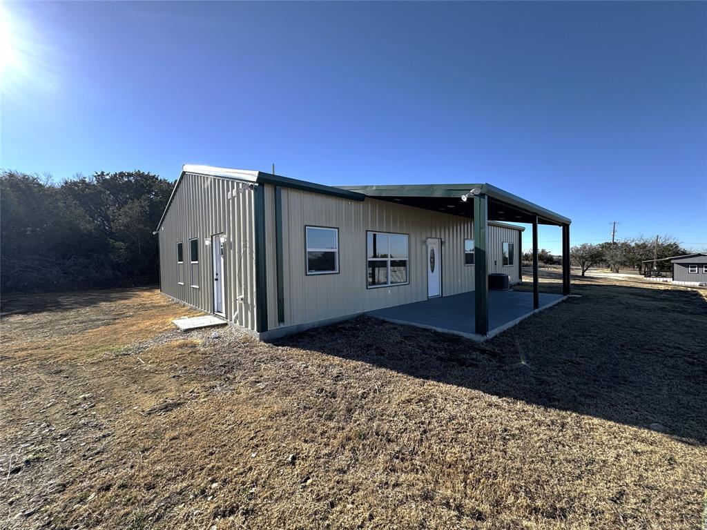 Affordable country living awaits in this newly built barndominium styled home set on 1.54 acres atop a gentle hill. The open-concept layout features soaring vaulted ceilings in the living room and a spacious island kitchen designed for gathering. The primary suite sits just steps from the oversized laundry room and includes a well-appointed bathroom and a generous walk-in closet. With a split-bedroom design, everyone enjoys added privacy. Relax on the large back porch and take in the peaceful spring evenings overlooking the Silverado Ranch which ensures backyard privacy. A separate storage building provides plenty of space for tools, equipment, and outdoor essentials. A versatile property with endless possibilities. 200 feet or asphalt drive and a concrete pad at the house means plenty of parking space.  Slab was pre-treated for termites.
