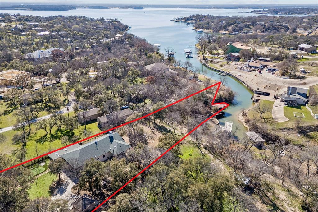 Stunning lakefront retreat on Eagle Mountain Lake with no HOA, situated on over 1.6 acres! This beautifully gated property welcomes you with a circular drive and exceptional curb appeal. The main home is beautifully updated and truly move in ready, featuring new flooring, fresh paint, a remodeled kitchen, and upgraded guest and primary bathrooms. All four bedrooms are conveniently located on the first floor along with a dedicated office space. Upstairs offers exceptional versatility with three flex rooms, currently used as a playroom, an additional living and movie room, and a separate office combined with a golf simulator space. Major system upgrades include a new HVAC, tankless water heater, propane tank, septic system improvements, and a replaced gate motor, providing peace of mind for years to come. Step outside to enjoy resort style living with a fully equipped outdoor kitchen, automated porch screens, putting green, and permanent exterior LED lighting. Additional conveniences include LeafFilter gutters and an EV charging station. Walk down to your private boat slip and enjoy effortless access to Eagle Mountain Lake. The newly completed guest house adds incredible flexibility, complete with a private bedroom, full bathroom, laundry room, and a spacious open concept living area with kitchen. Just outside, a dedicated game room space makes this setup ideal for entertaining guests or multi generational living. Conveniently located near everything Fort Worth has to offer and zoned for the new Eagle Mountain High School, this exceptional property blends luxury, comfort, and an unbeatable lake lifestyle.