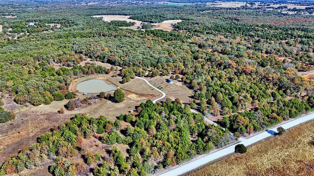 GATED RETREAT OFFERING PEACE AND PRIVACY!   This meticulously manicured 33.59ac property presents recreational capabilities and residential possibilities all rolled into one breathtaking setting.  Located on the Cooke Co side of western Whitesboro, you will discover a unique oasis hidden by mature trees and a gentle roll, along with added tax savings in the form of an annually approved wildlife exemption.  Discover your own future homesite or take advantage of the two, fully furnished cabins and separate bathhouse that have been generating supplemental rental income on Airbnb for the owners.  Added charm and convenience may be found with individual grilling stations and a carport at each cabin, a fire pit, an outdoor kitchen, and covered RV parking with hook ups.  Across the well-maintained gravel driveway, you will spot geese flocking towards a gorgeous pond.  Paddle boating, fishing, relaxation and wildlife watching are just a few of the perks that you may experience.  If hunting appeals more to your tastes, 2 tree stands, a two-seater deer blind, 3 spin feeders and one lg gravity feeder will convey along with 2 four-wheelers and 2 lawn mowers.  The land is fenced with good, barbed wire fencing and distinct walking or riding trails are evident throughout.  Mixed fruit trees, pecan trees, and black berry bushes flank the driveway.  Co-op electric, City of Callisburg water, and a 3yr old septic system mean all utilities are installed and ready for your next adventure.
